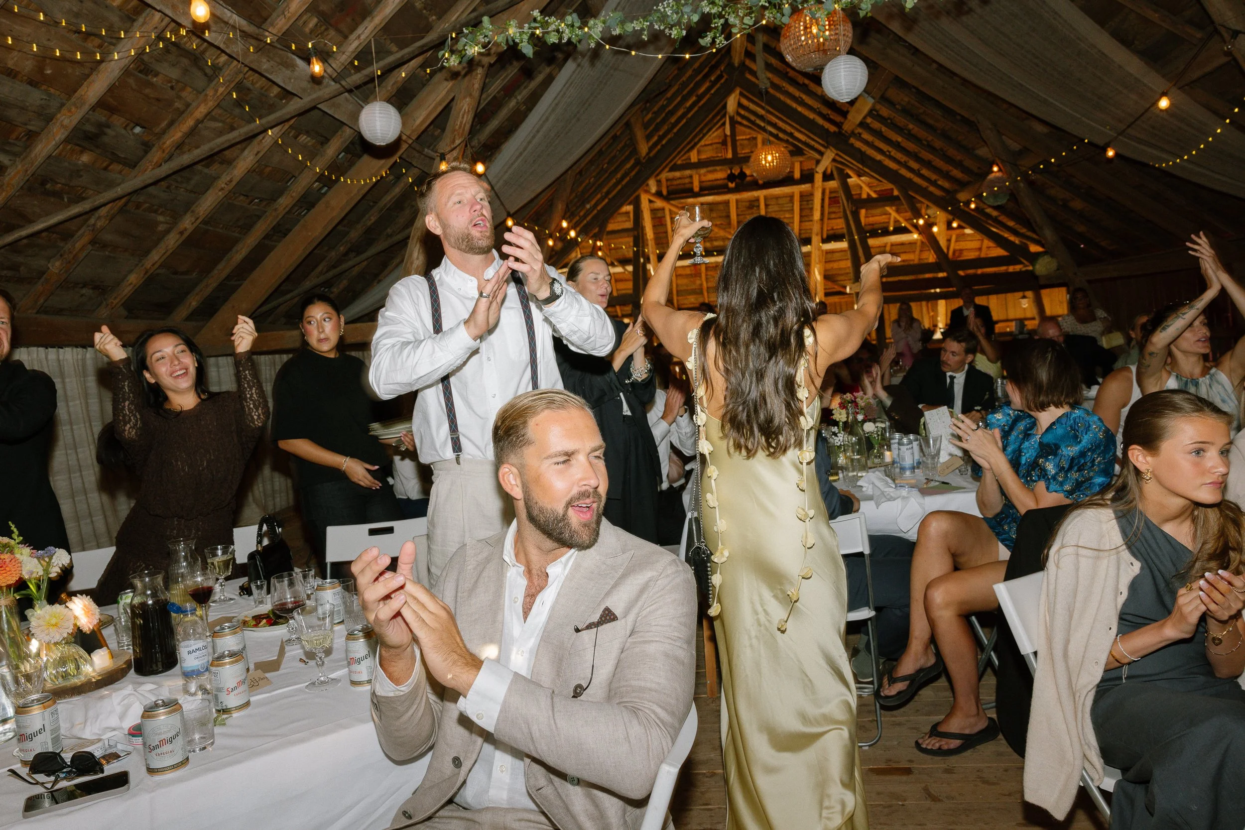 Folk som dansar och har roligt på ett inomhusbröllop eller fest i en lada .  Av Sofia Wilhelmina bröllopsfotograf i Stockholm.