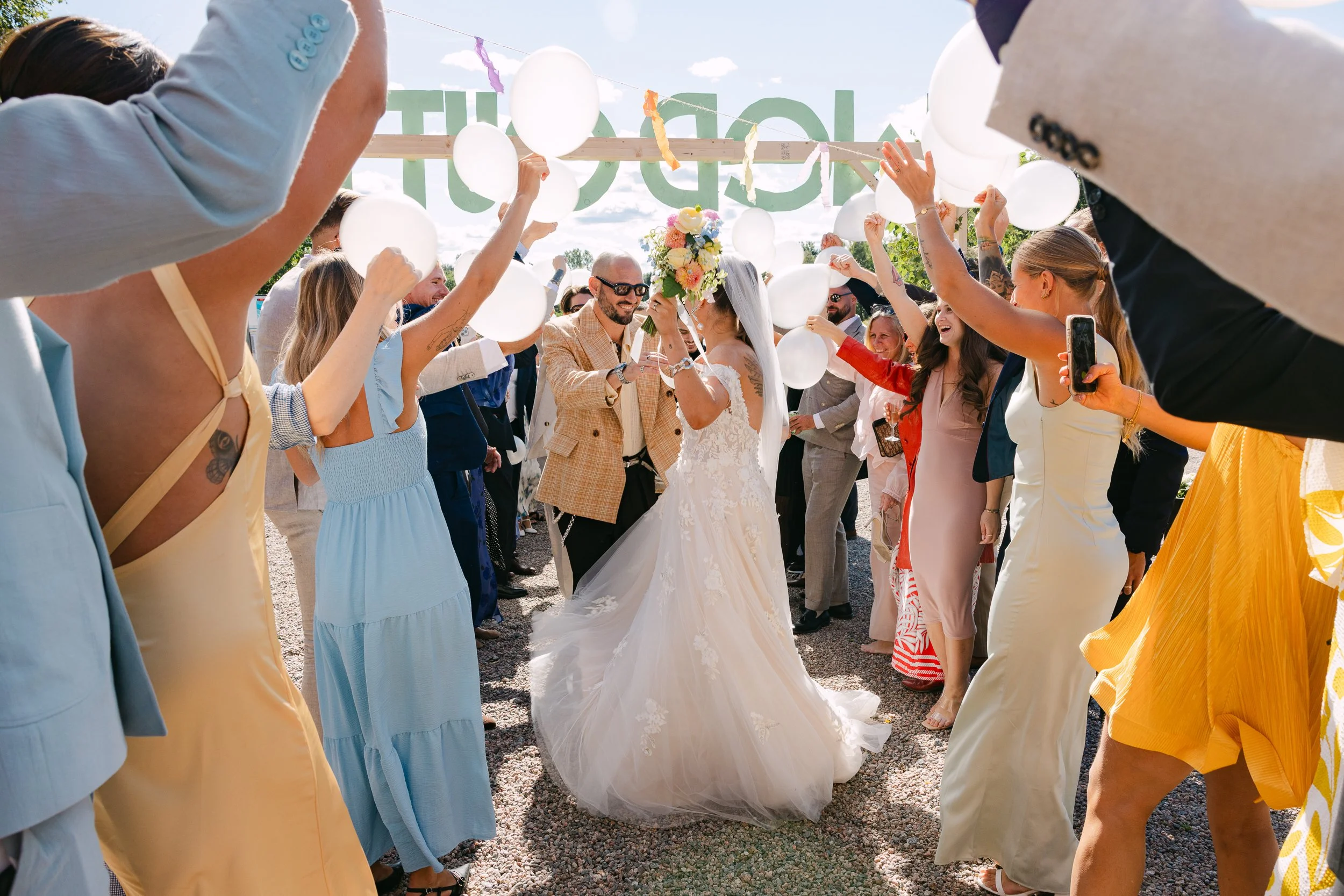 En brud och en brudgum som dansar omgiven av gäster på en utomhusbröllopsfest, med vita ballonger och festdekorationer.  Av Sofia Wilhelmina bröllopsfotograf i Stockholm.