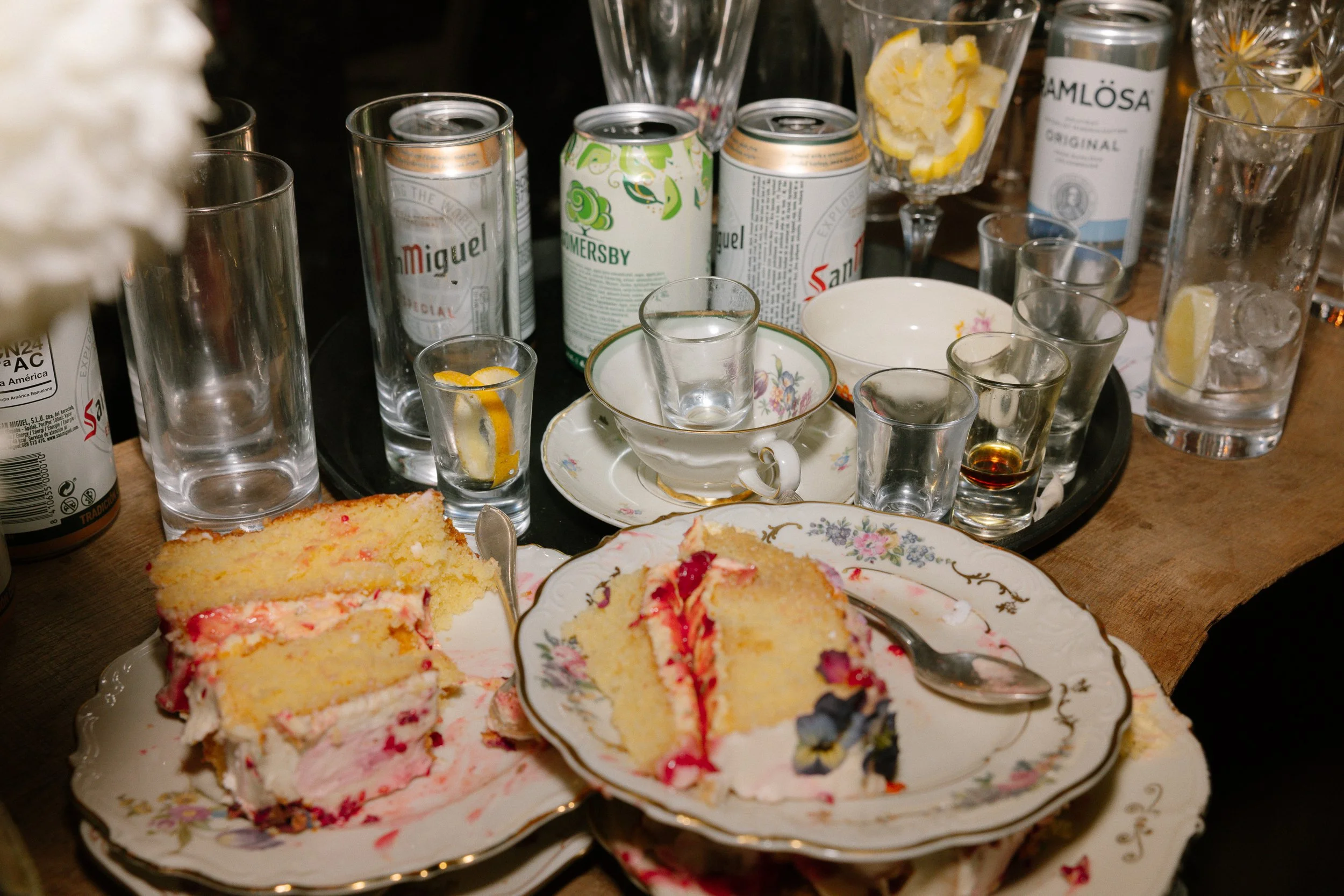 Rester av tårta och tomma glas, sedda på ett dukat bord.