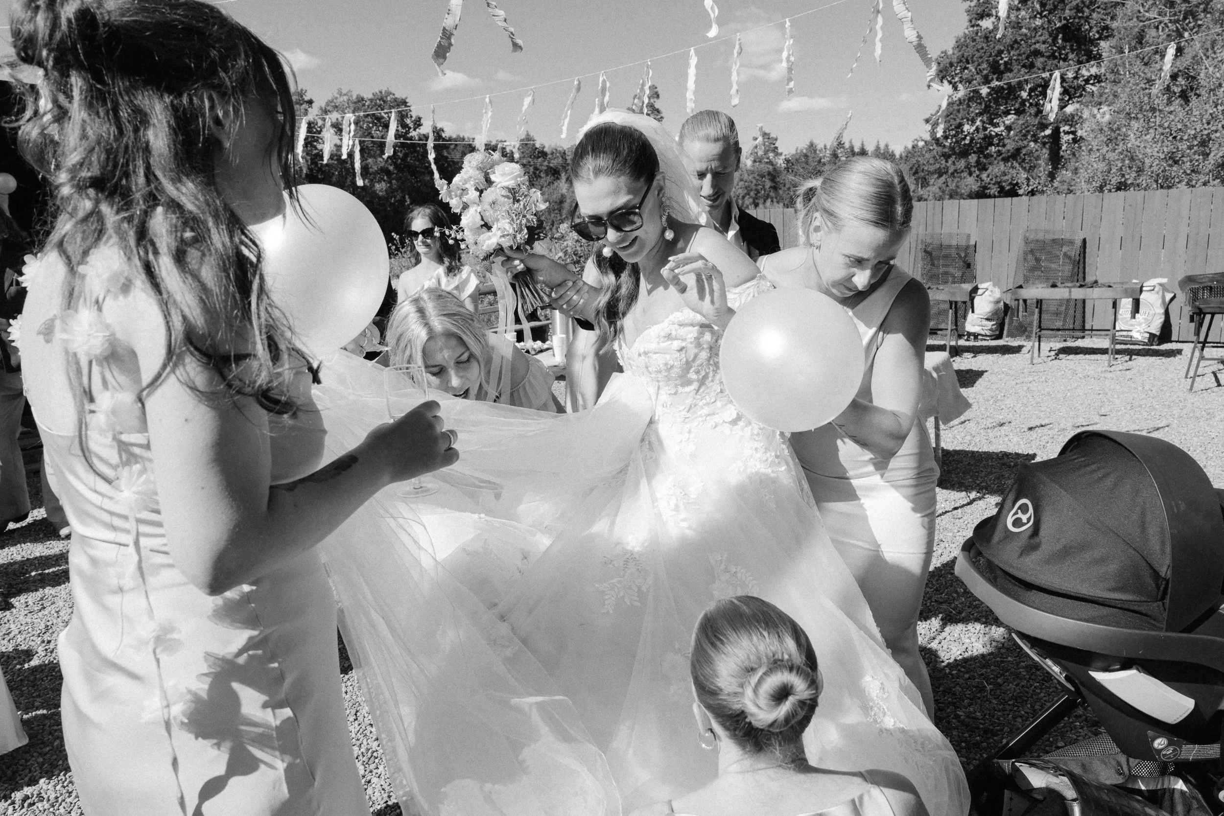 En grupp kvinnor, inklusive en brud i bröllopskläder,  utomhus vid ett bröllop.  Av Sofia Wilhelmina bröllopsfotograf i Stockholm.