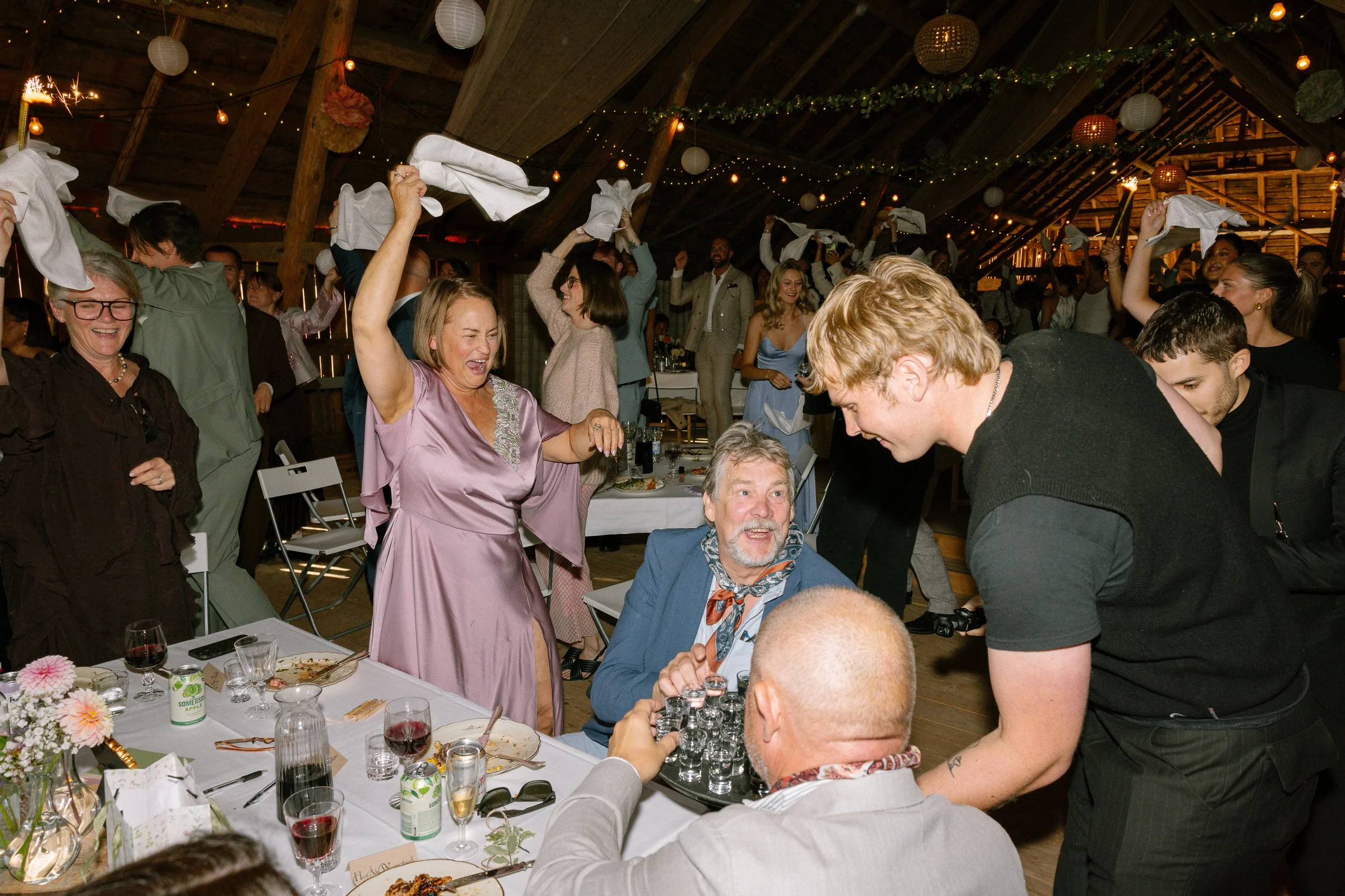 Människor som dansar och har roligt vid en bröllopsfest på en loge med belysning och papperslyktor.  Av Sofia Wilhelmina bröllopsfotograf i Stockholm.