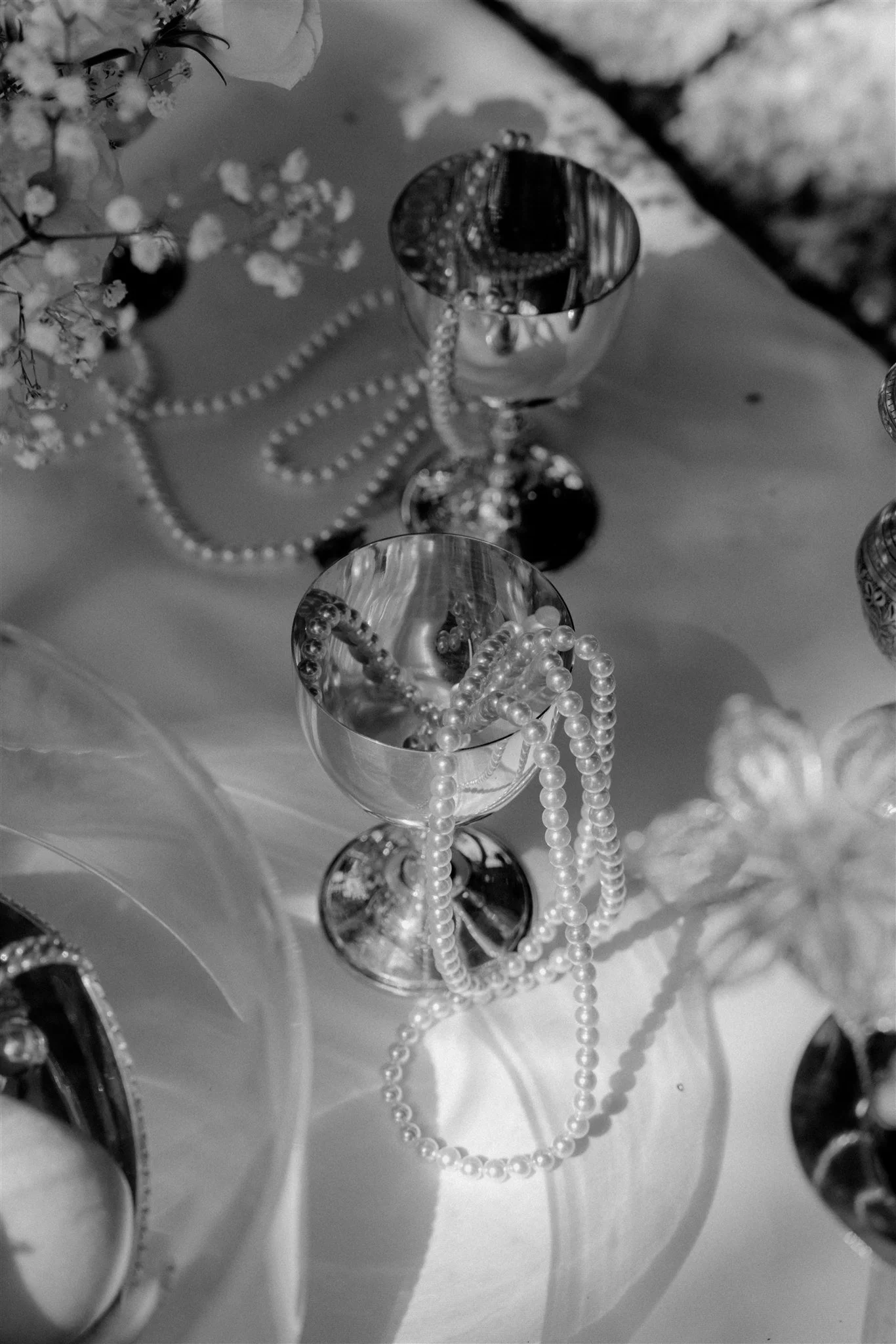 Pearl strands draped over silver candle holder on Sofreh Aghd