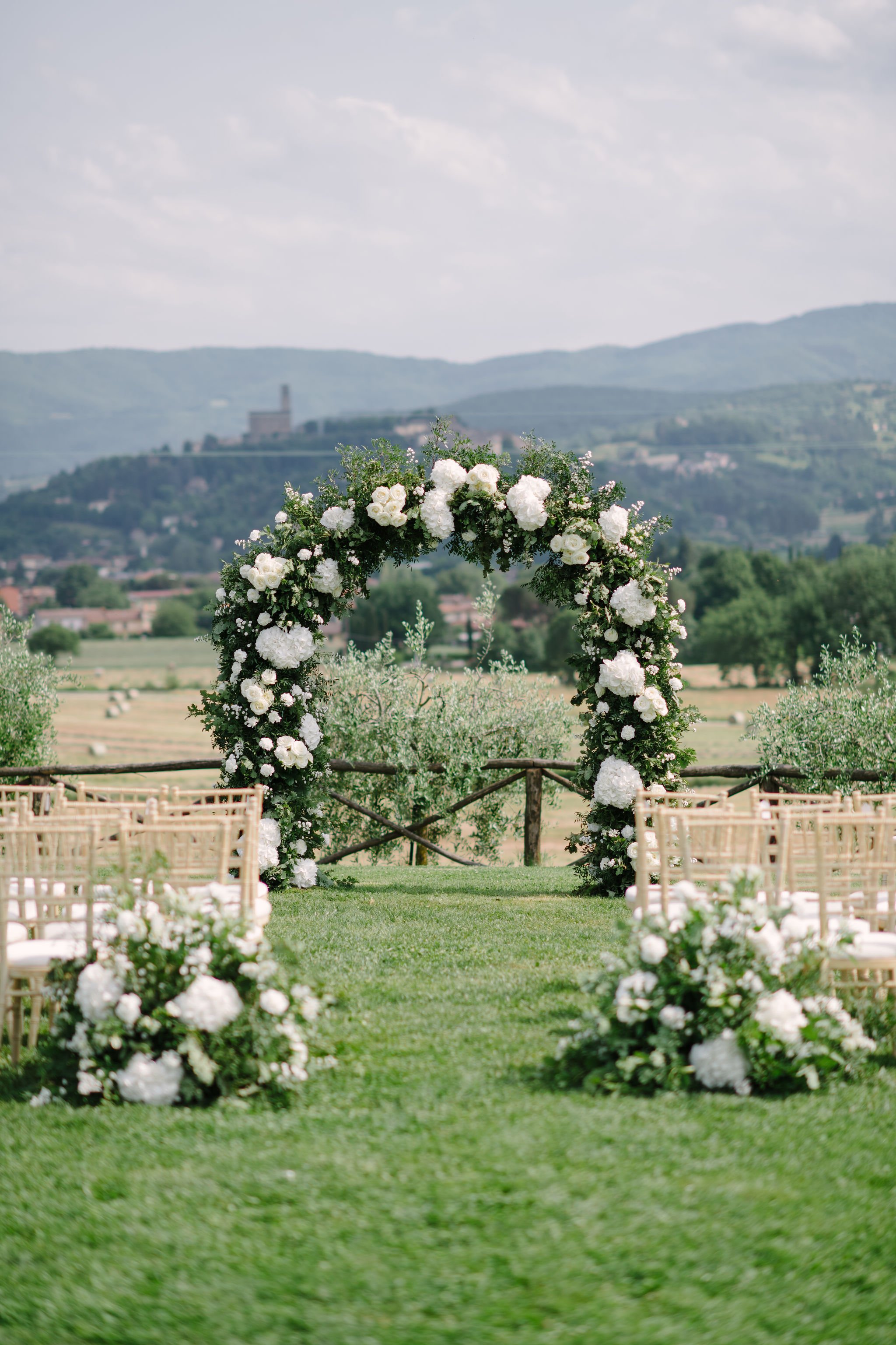 ceremony arch with white flowers and tuscan backdrop