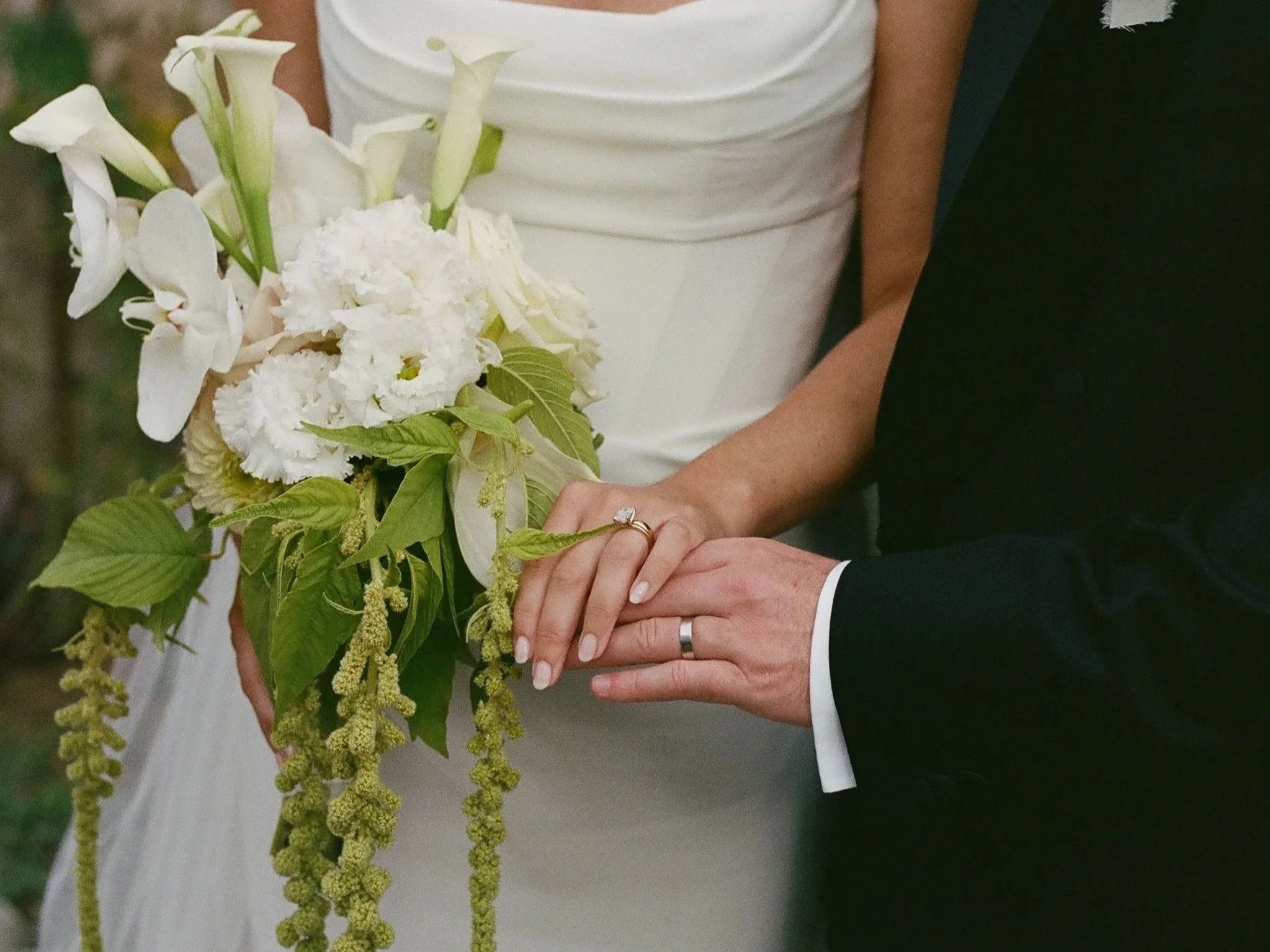 Bride and groom holding hands and the white and green bouquet