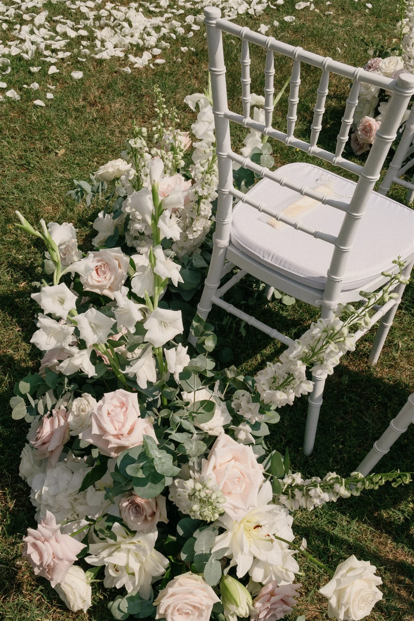 Blush and white ceremony flowers lining aisle chairs in Tuscany