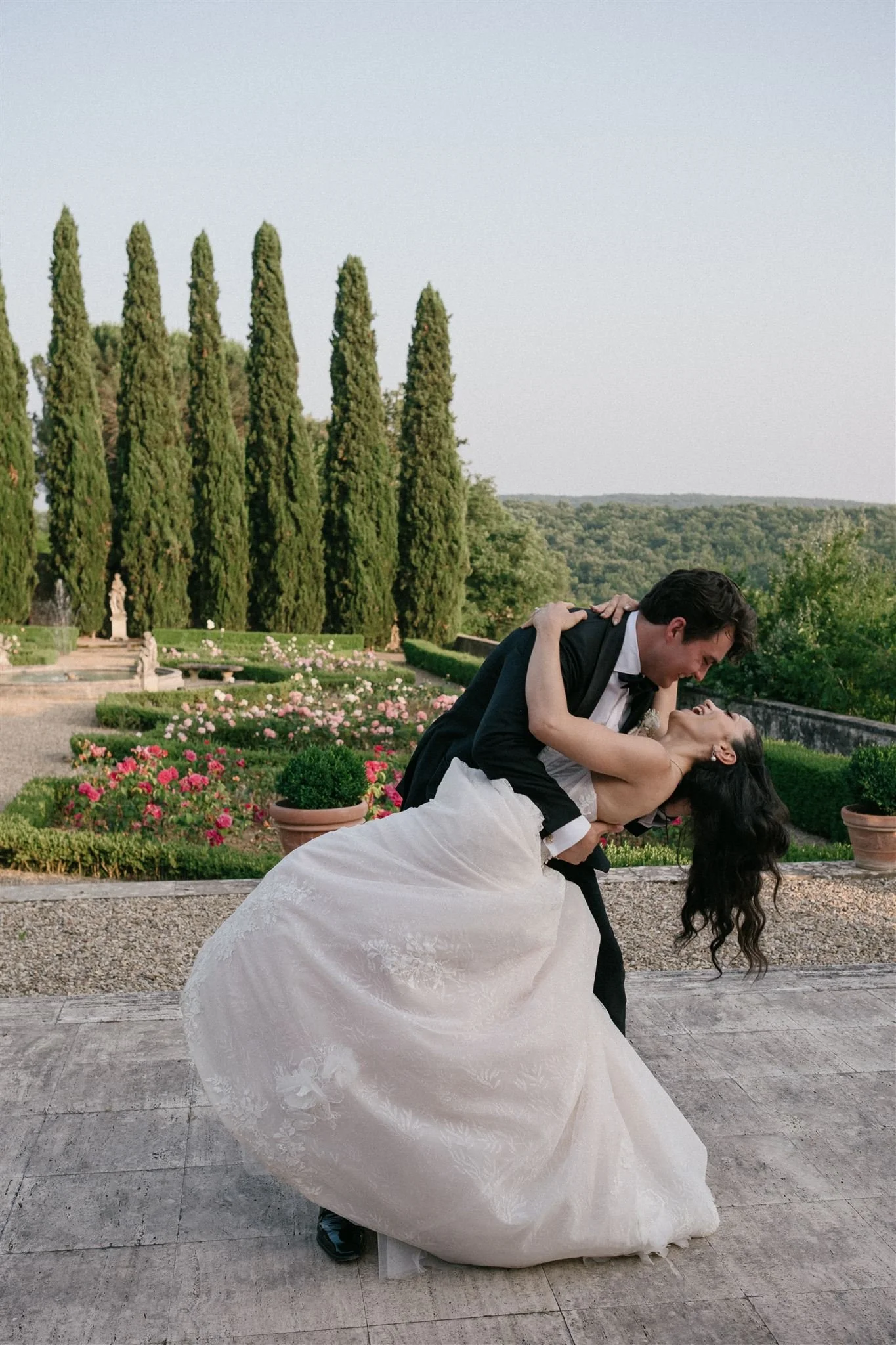 Groom dipping bride in formal Italian garden