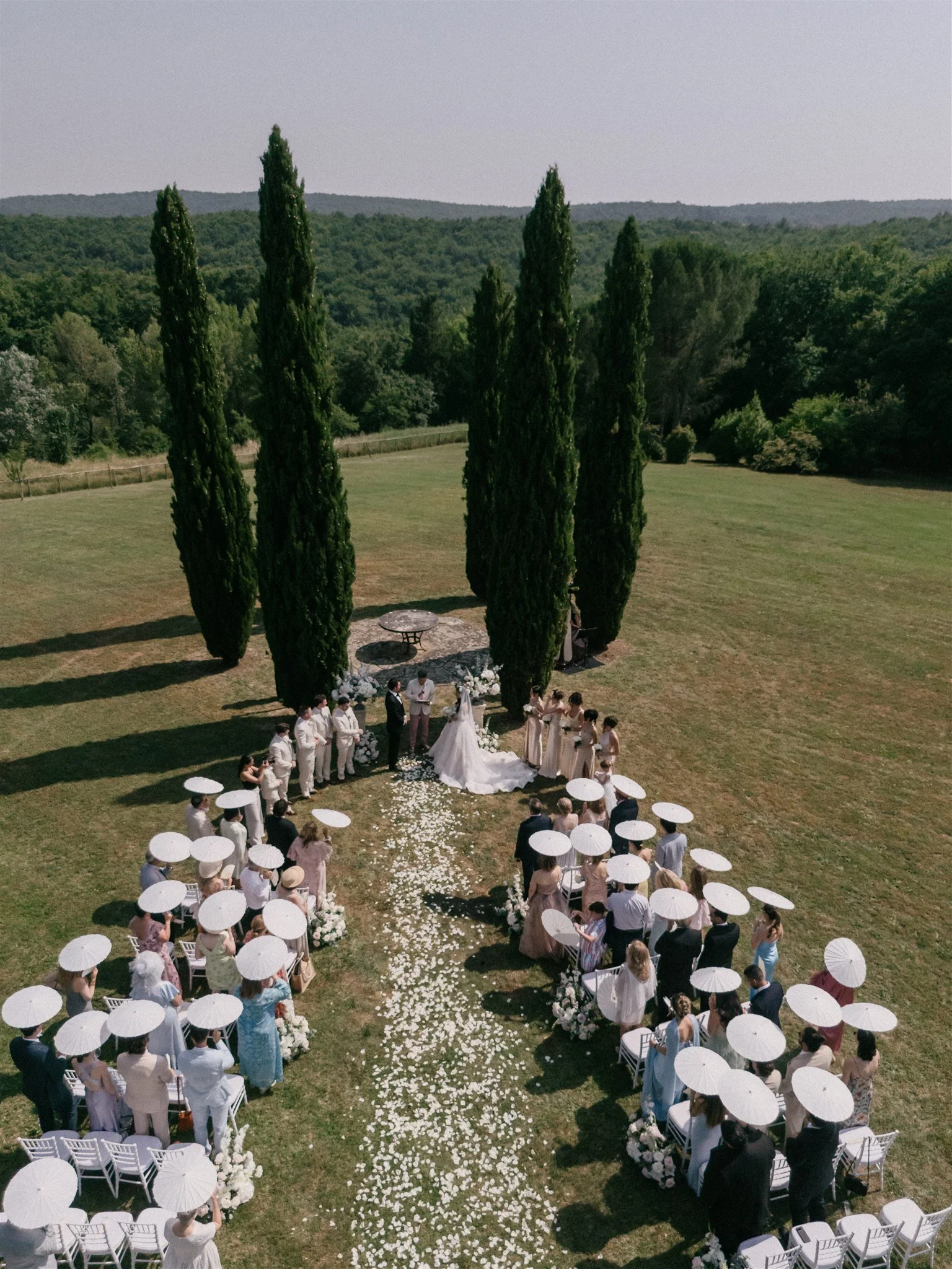 Overhead view of guests gathered beneath cypress trees in Tuscany