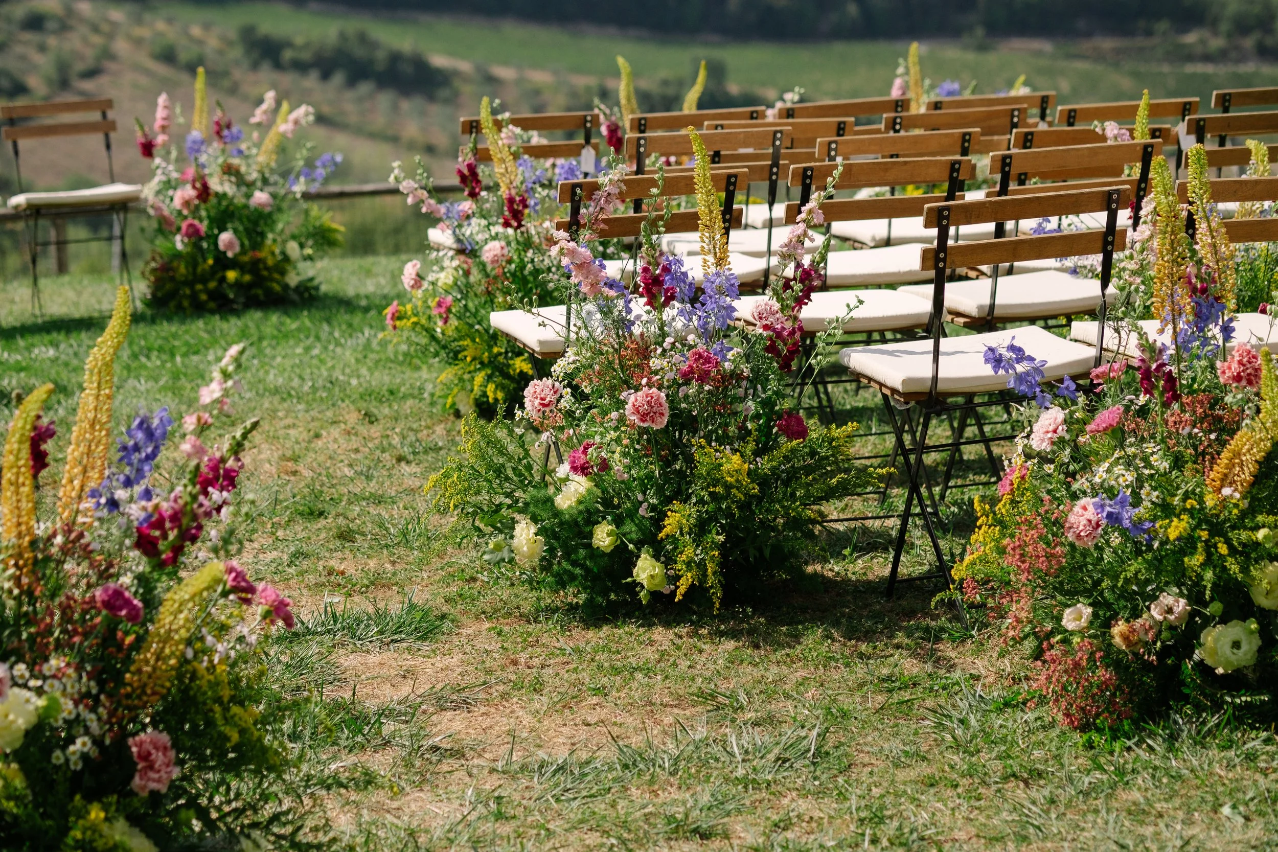 floral arrangements placed on the ground next to aisle chairs