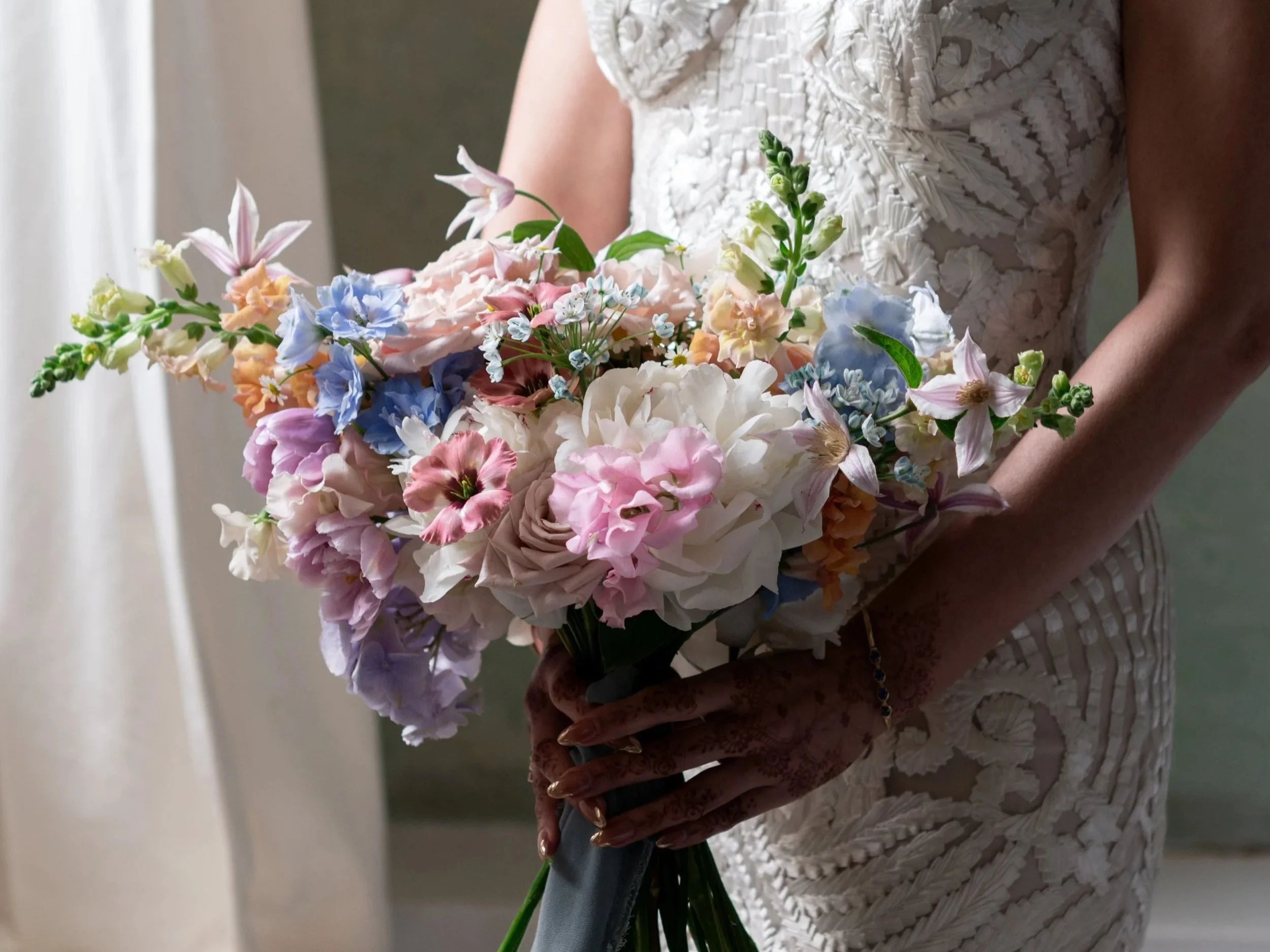 Bride holding a wildflower unstructured bouquet with pastel flowers