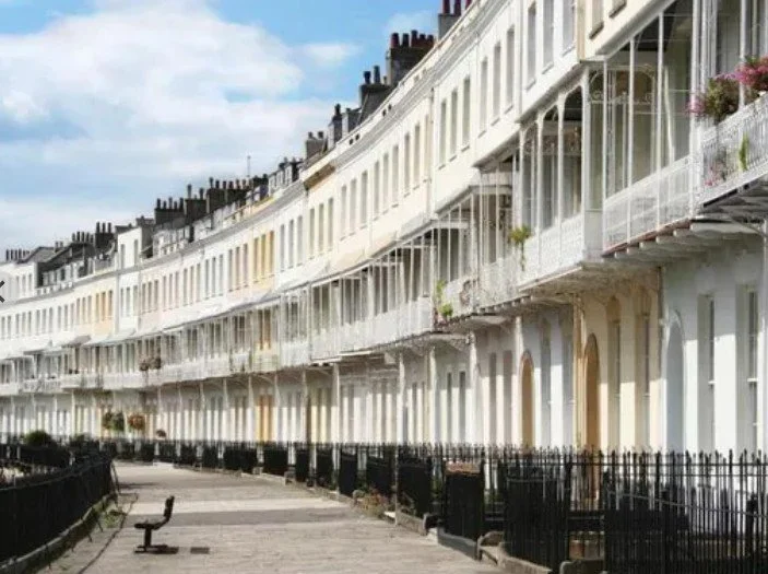Row of white, Victorian-style terraced houses with balconies on a curved street