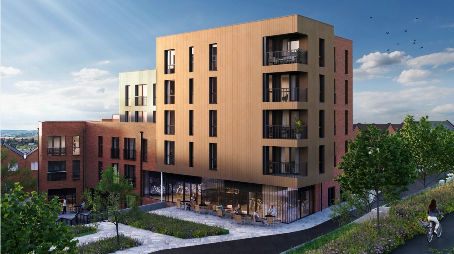 Modern multi-story residential building with brick and beige exterior, balconies, and large glass windows, surrounded by greenery and a paved outdoor seating area.