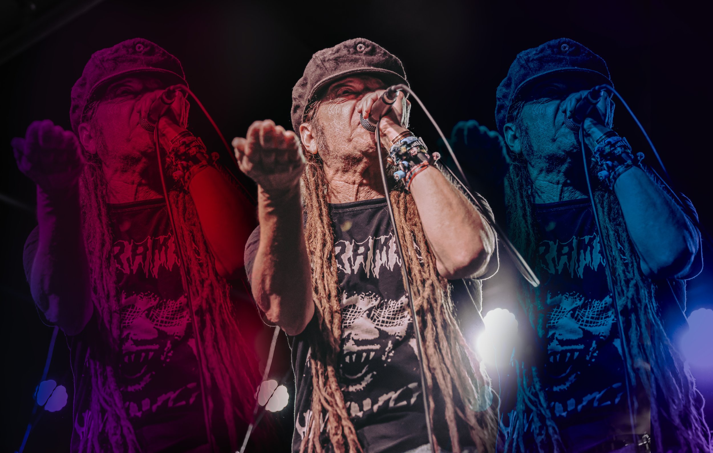 A man with long dreadlocks singing into a microphone on stage, wearing a black cap and a graphic T-shirt, with stage lighting creating a colorful double exposure effect showing him in pink, white, and blue variations