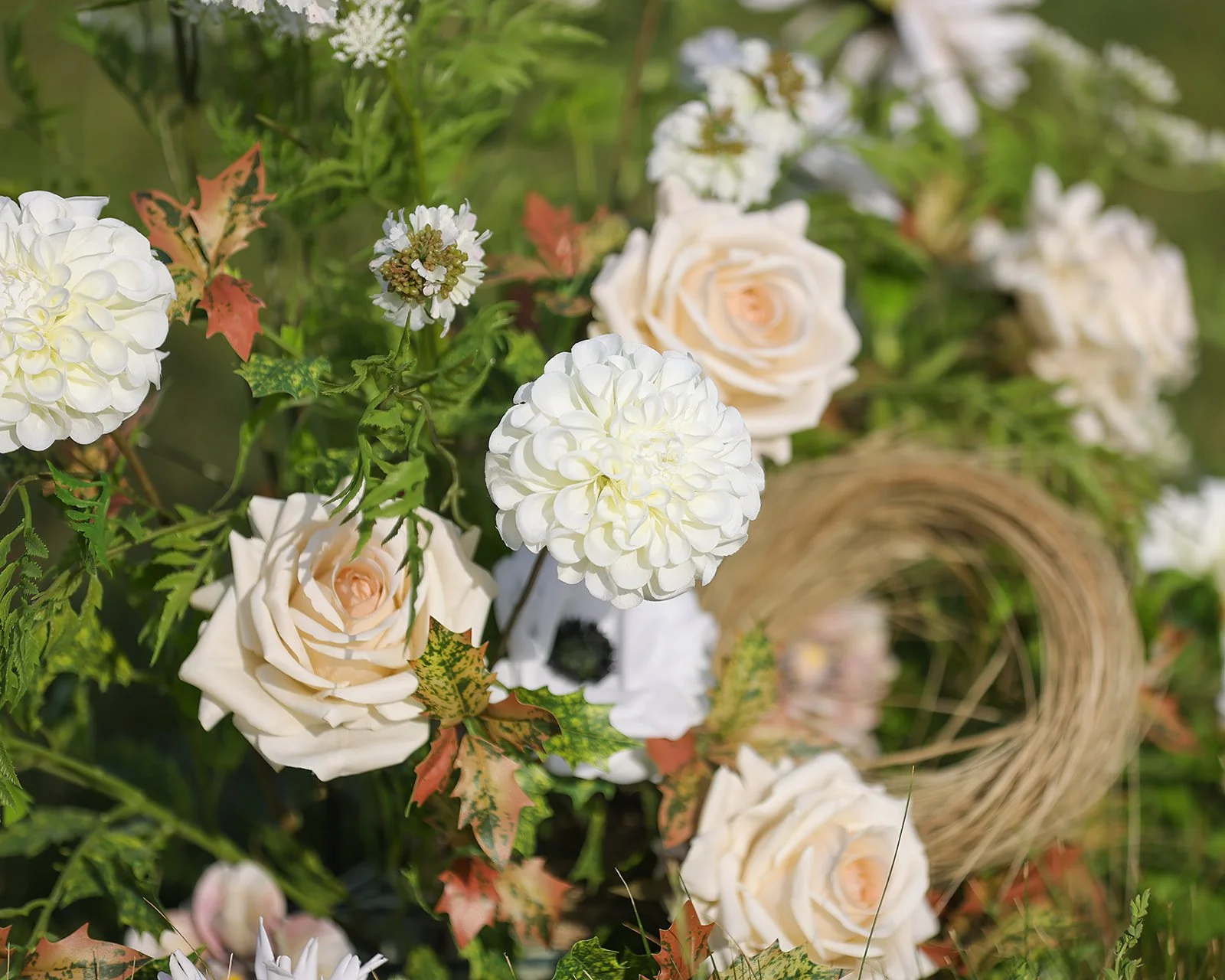 A whimsical and romantic bouquet with oranges, pinks and burgundy is held up against the sky by a bride's hand covered in a lace and sequined glove