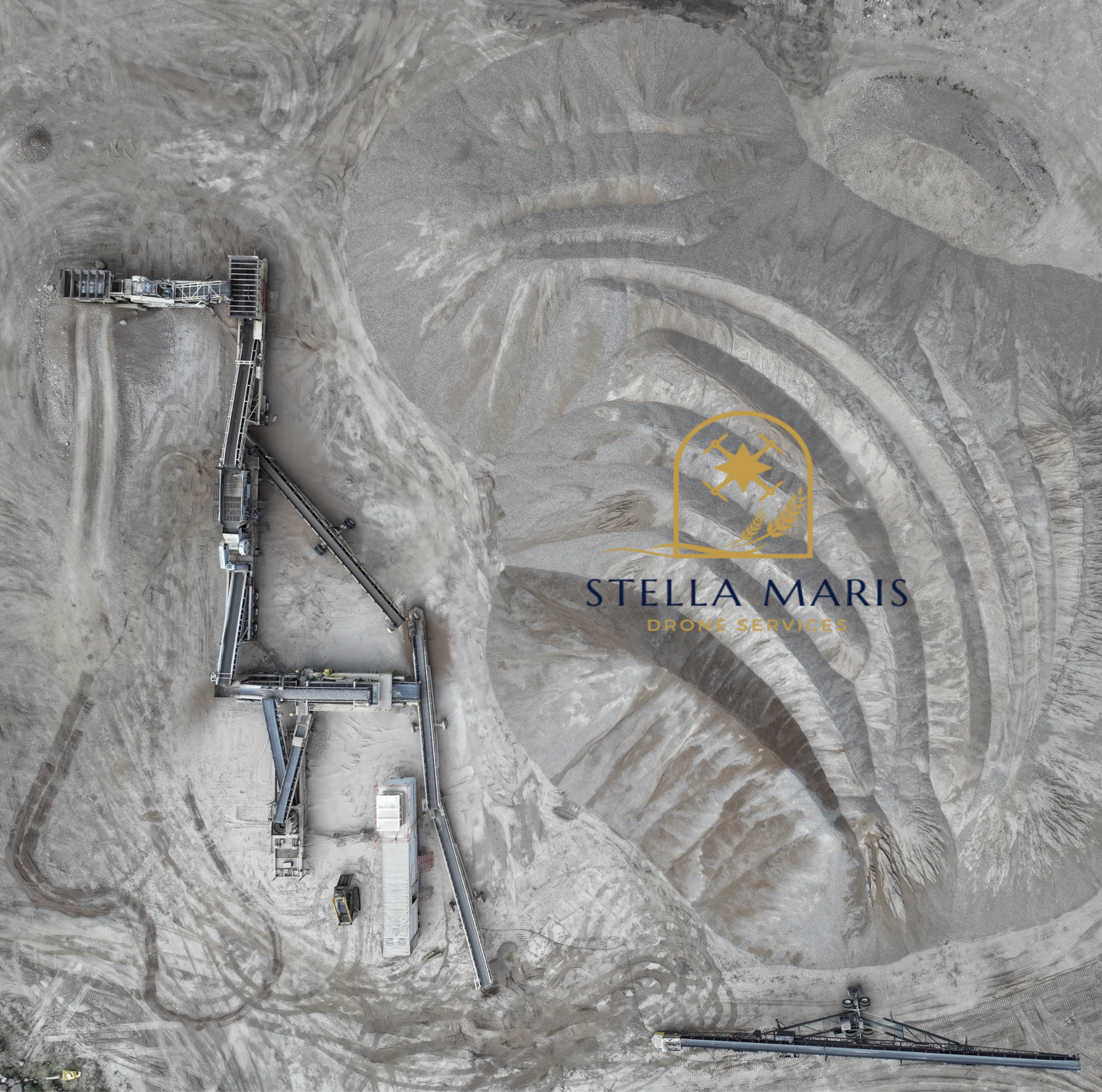 An aerial view of a large open-pit mining operation with conveyor belts and machinery in a desert-like area. There is a logo for Stella Maris Drone Services overlaid on the image.