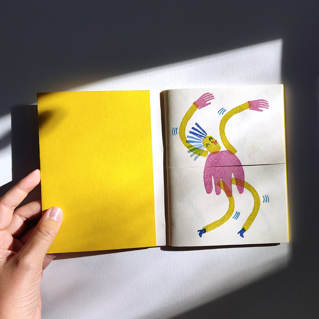Carnet ouvert avec couverture jaune et illustration colorée d'une figure abstraite à l'intérieur.