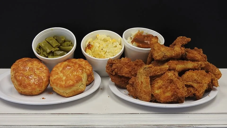 Plate of two fried chicken biscuits, a side of green beans, mashed potatoes with gravy, and pieces of fried chicken with dipping sauce at Southern Chicken in Surfside Beach, SC near Myrtle Beach, SC