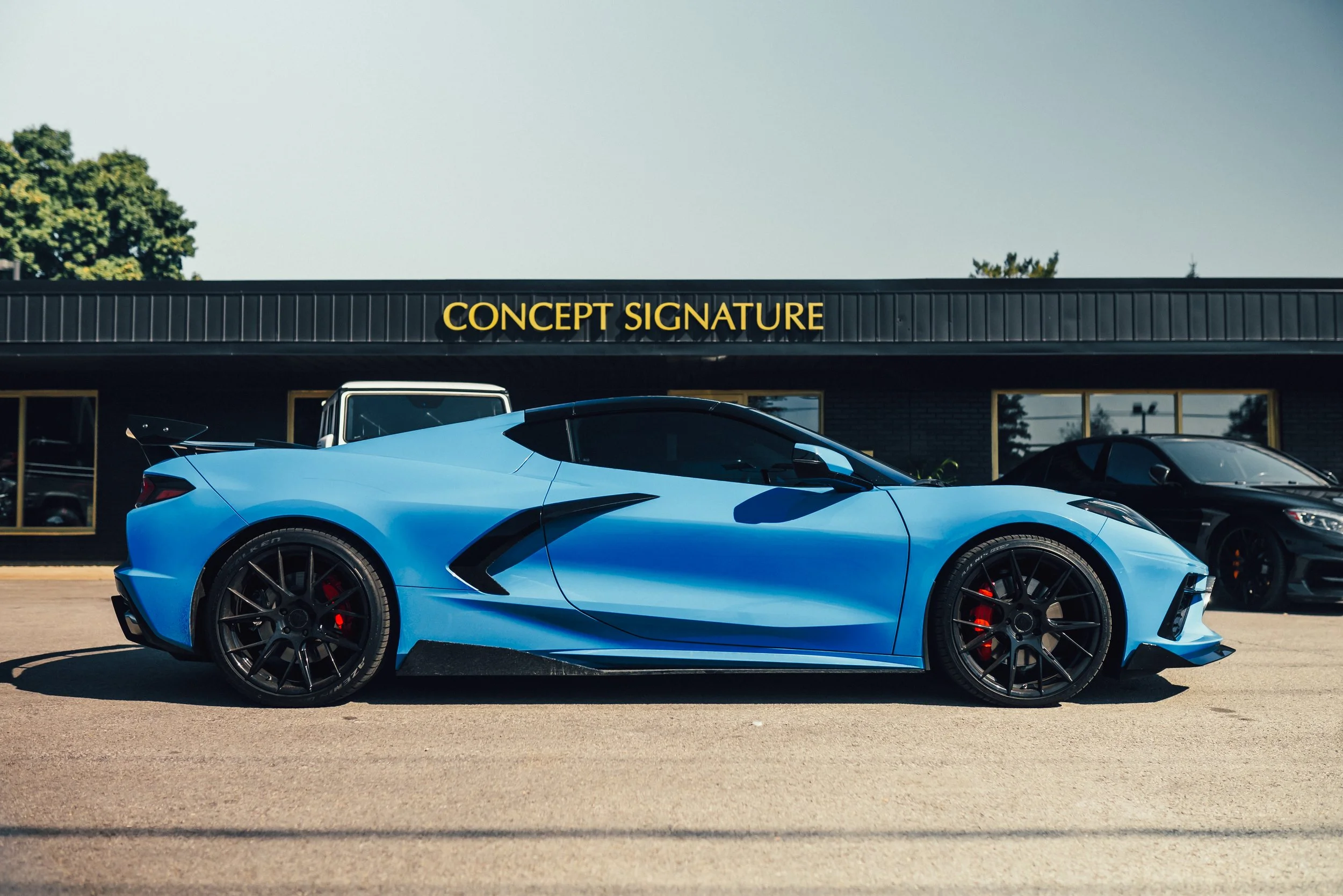 Blue sports car parked in front of a building with the words 'Concept Signature' on it.