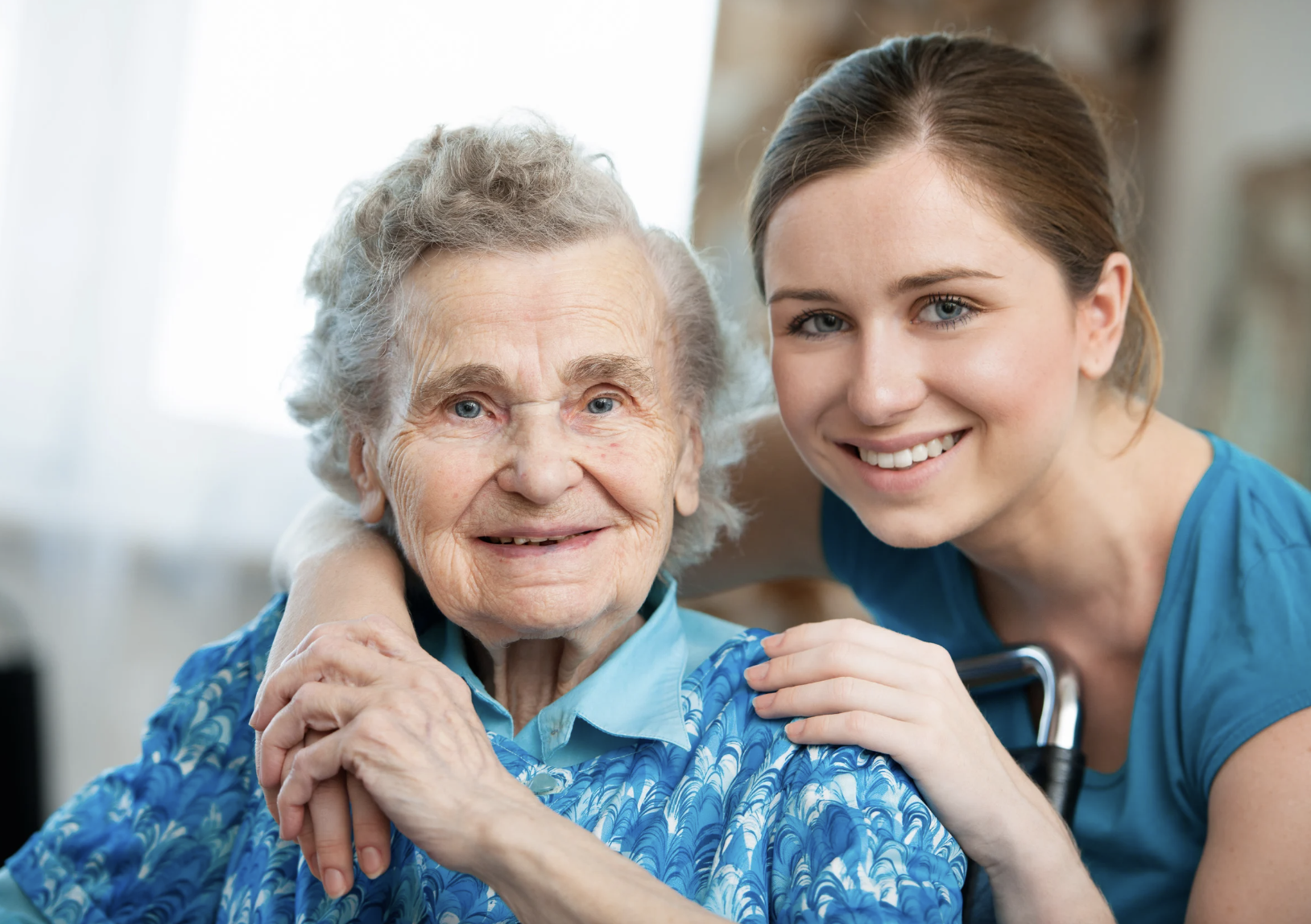 An elderly woman with gray hair and a young woman with brown hair smiling close together, showing affection and companionship.