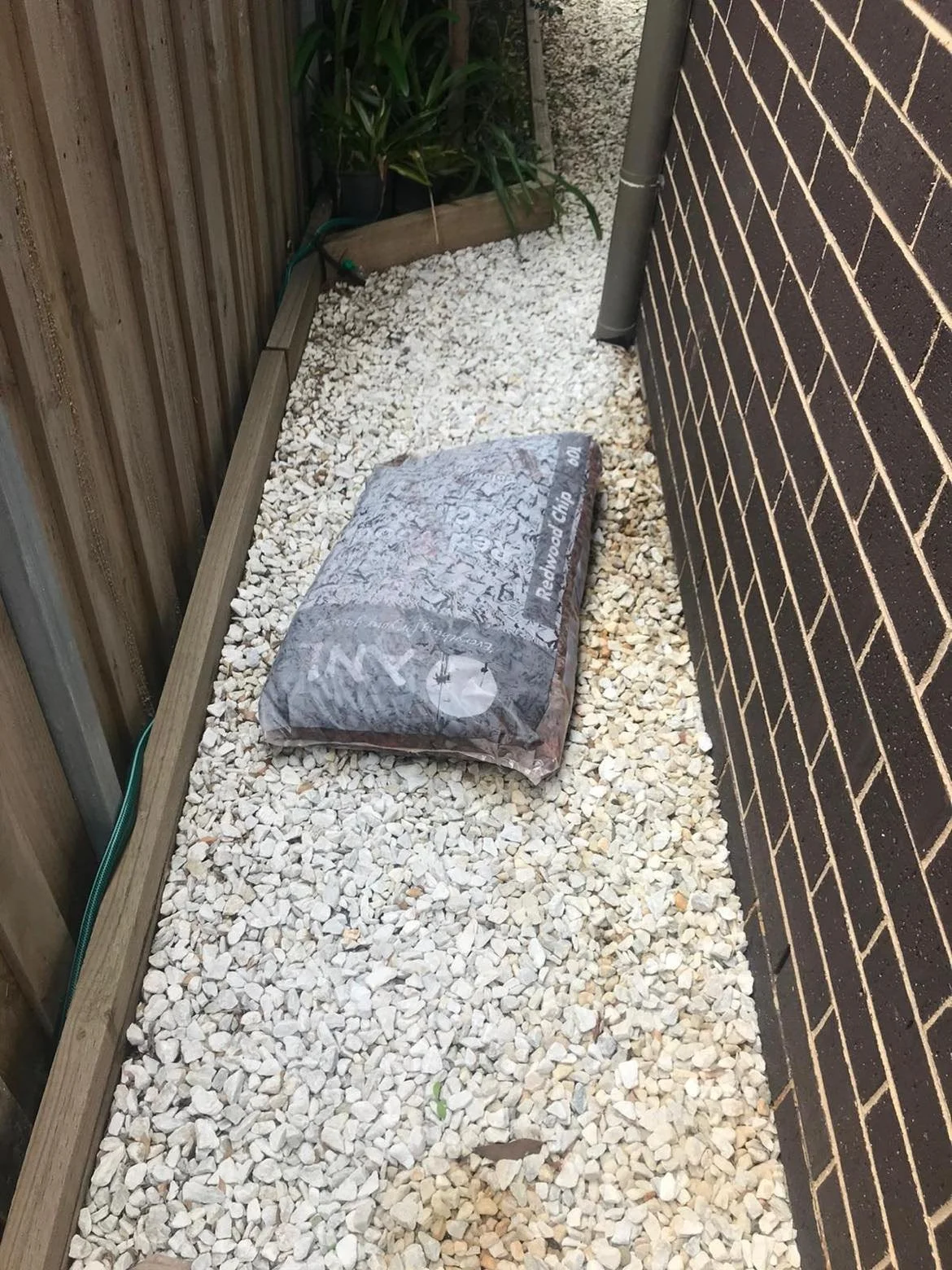 Bag of wood chips stored beside a home, creating a potential termite risk close to the building