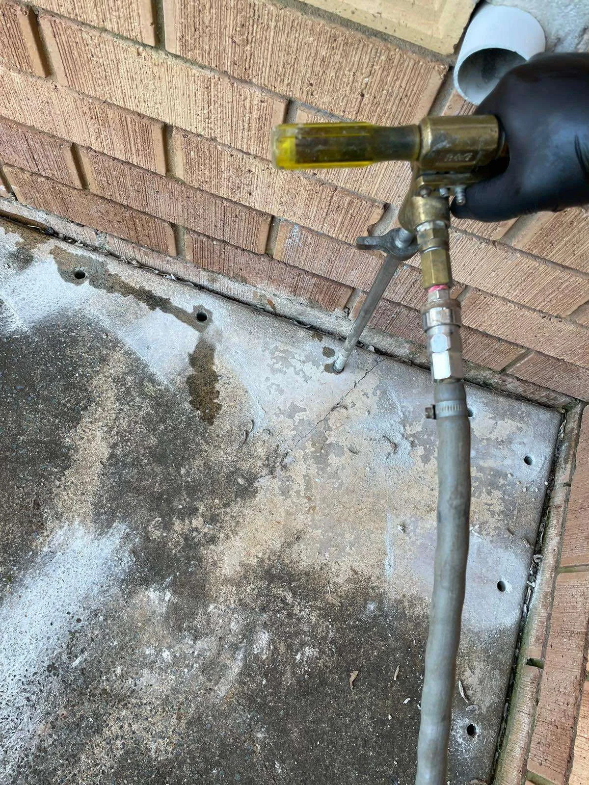 Chemical soil treatment being applied through drilled concrete for termite management