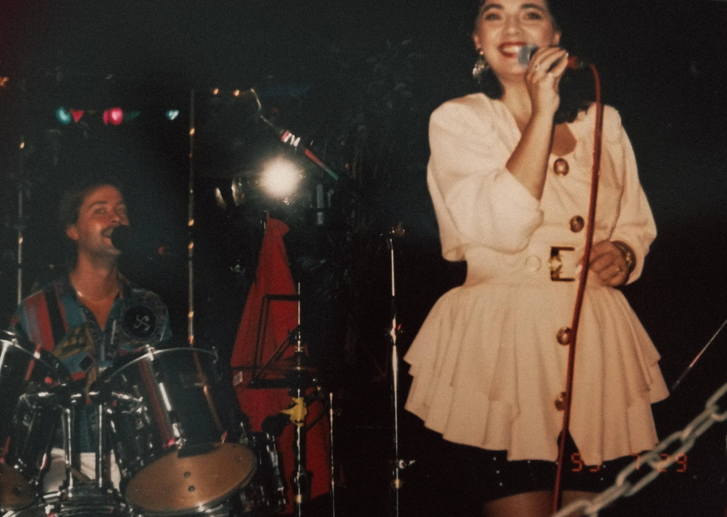 Kristiina Mäki esiintymässä Safir-yhtyeen kanssa.  Kristiina laulaa mikrofoniin ja mies soittaa rumpuja taustalla.