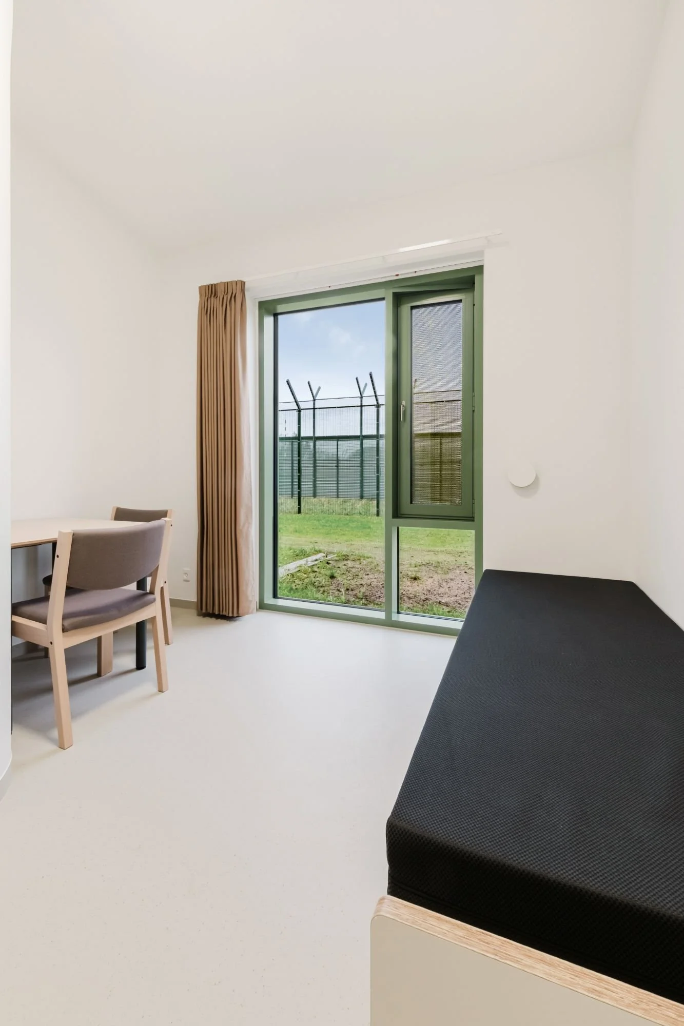 Interior view of a prison cell at Sønder Omme Prison with bed, desk, and window