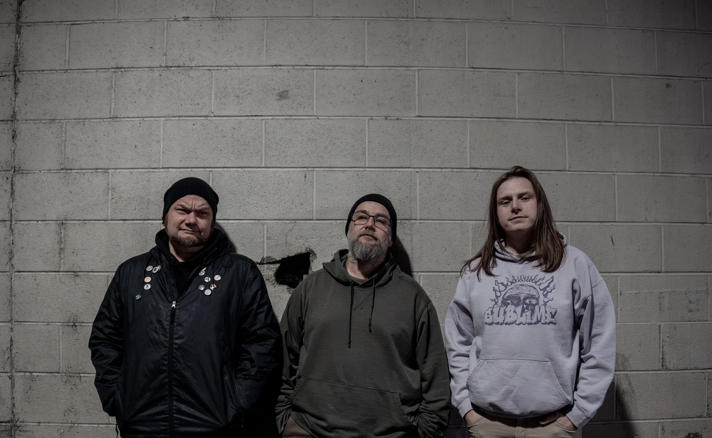 Members of the band Mr. Scientist against a concrete block wall.