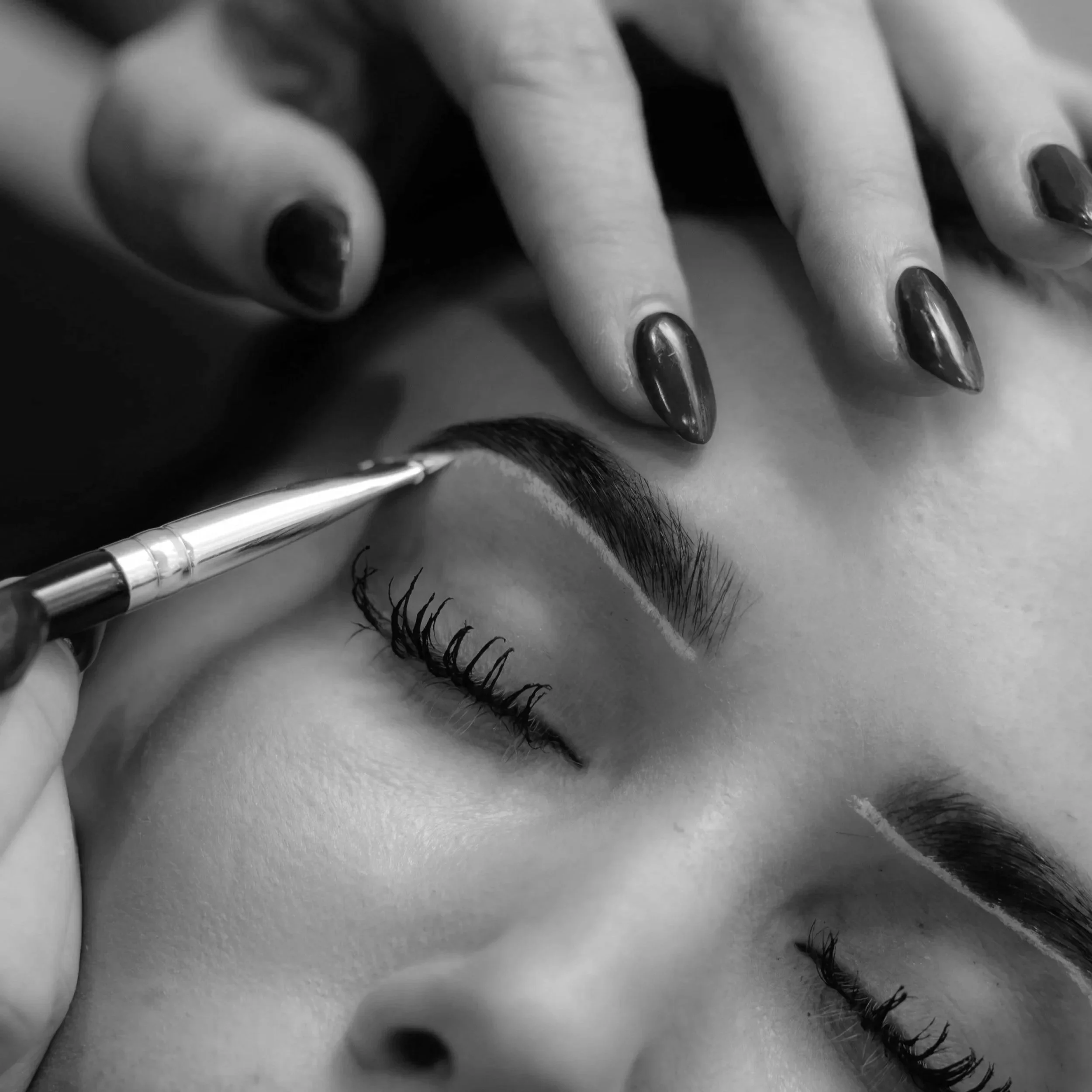 Close-up of a woman getting their eyebrows mapped by a brow artist at Mrakki Brow Bar.