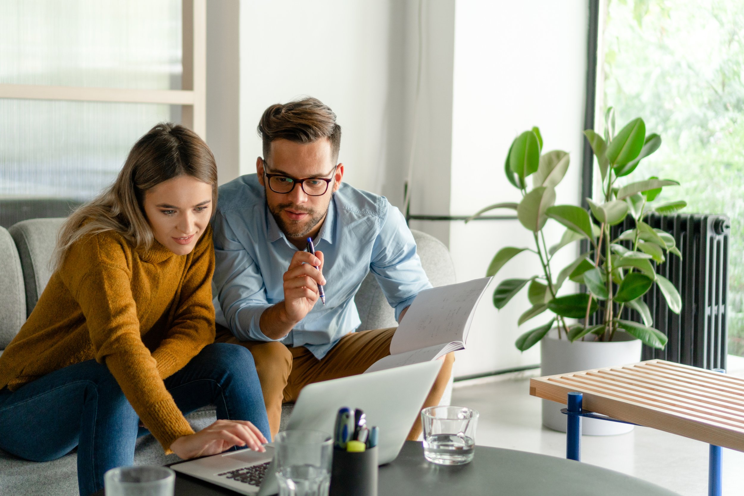 Two professionals reviewing information together on a laptop in a home office.