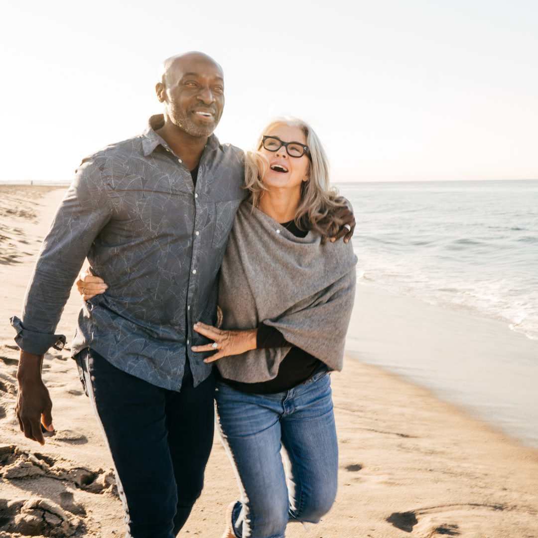 Two adults laughing together on a beach