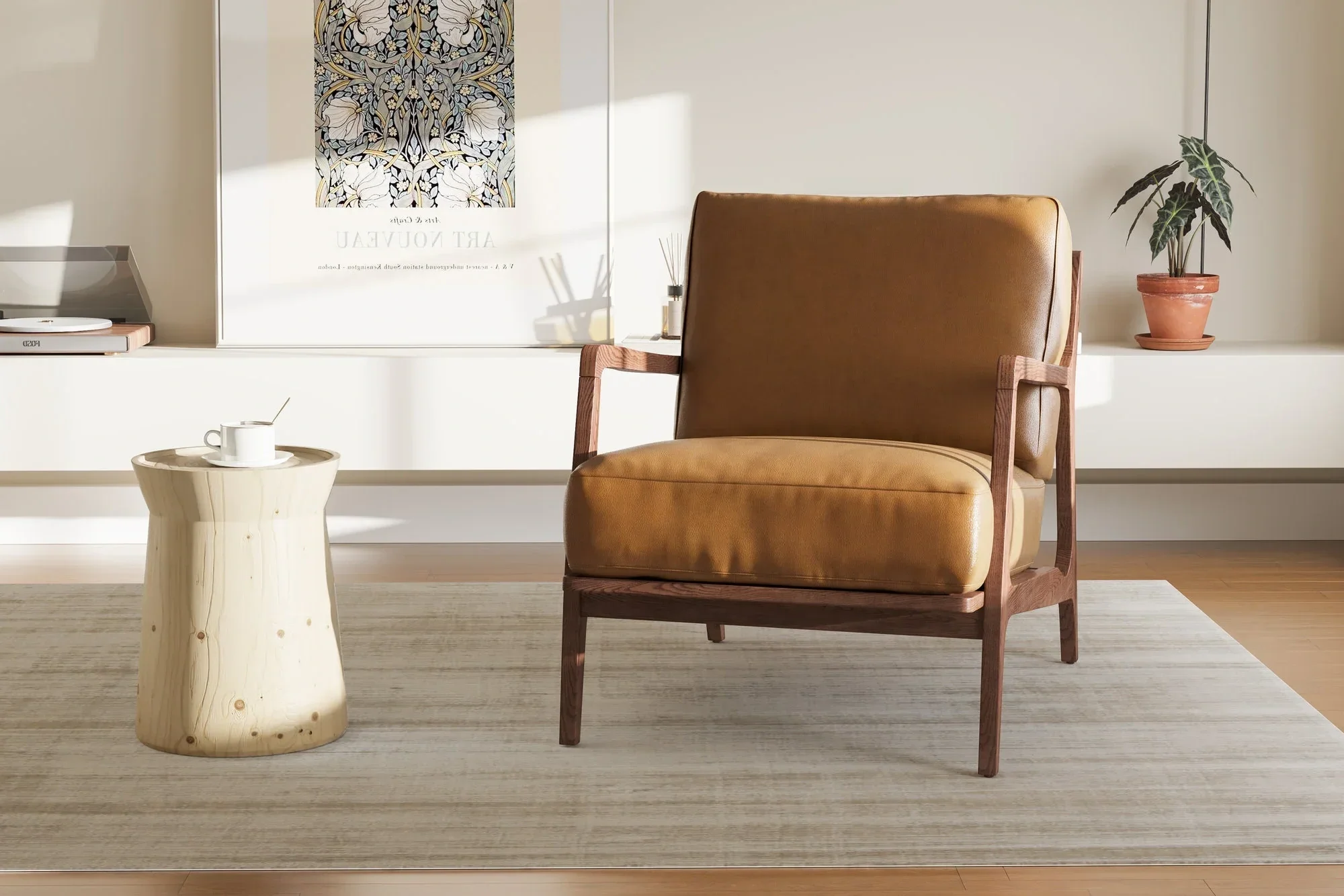 A cozy living room corner with a tan leather armchair with wooden arms, a light-colored small wooden side table with a cup and saucer, a white rug, a potted plant with dark green leaves, and a framed art nouveau poster on the wall.