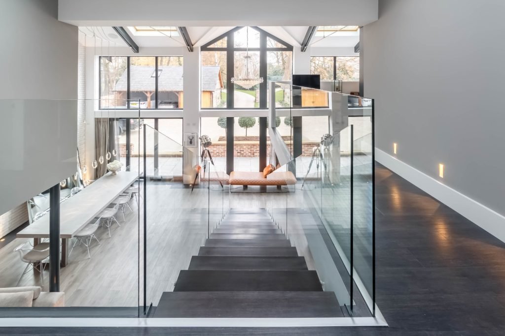Modern interior with glass stair railing, large windows, and dining area