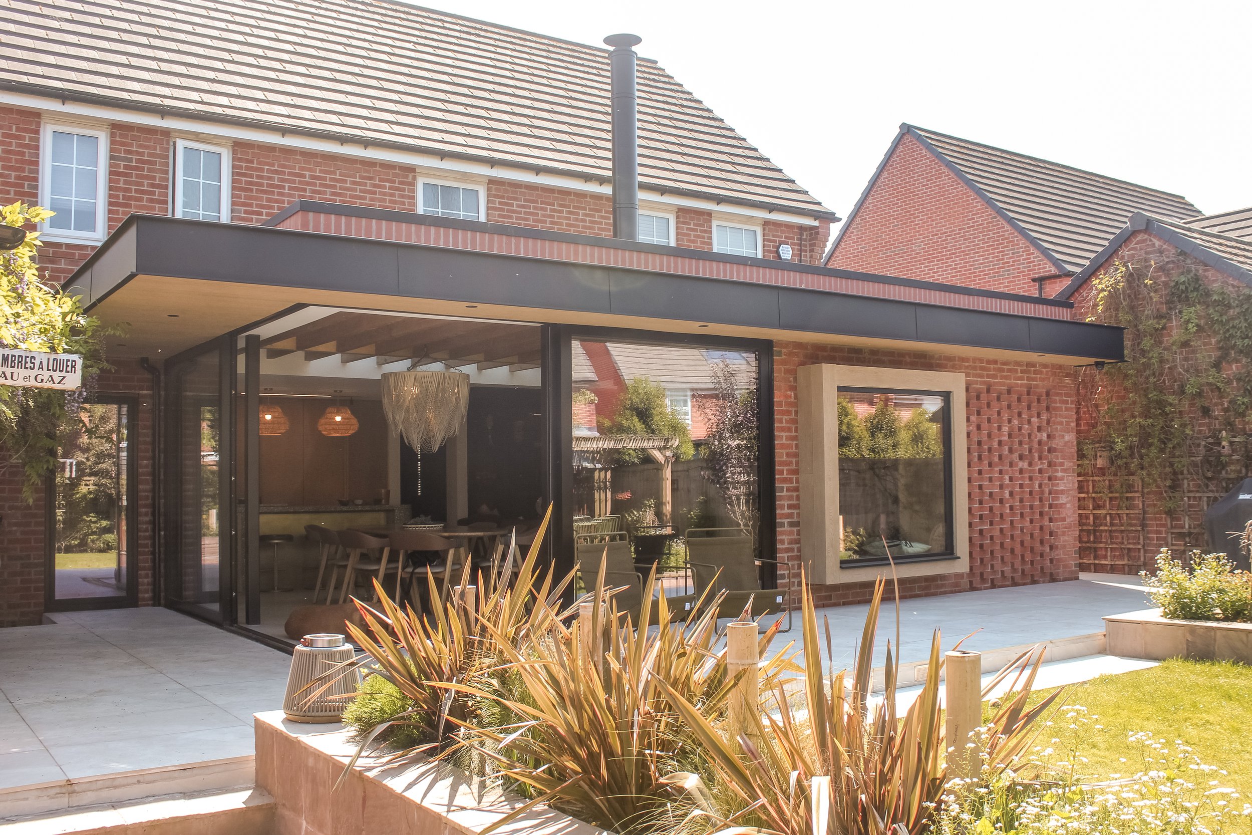 Space Architecture + Planning — Modern brick house with large glass windows, outdoor patio area, and landscaped garden.