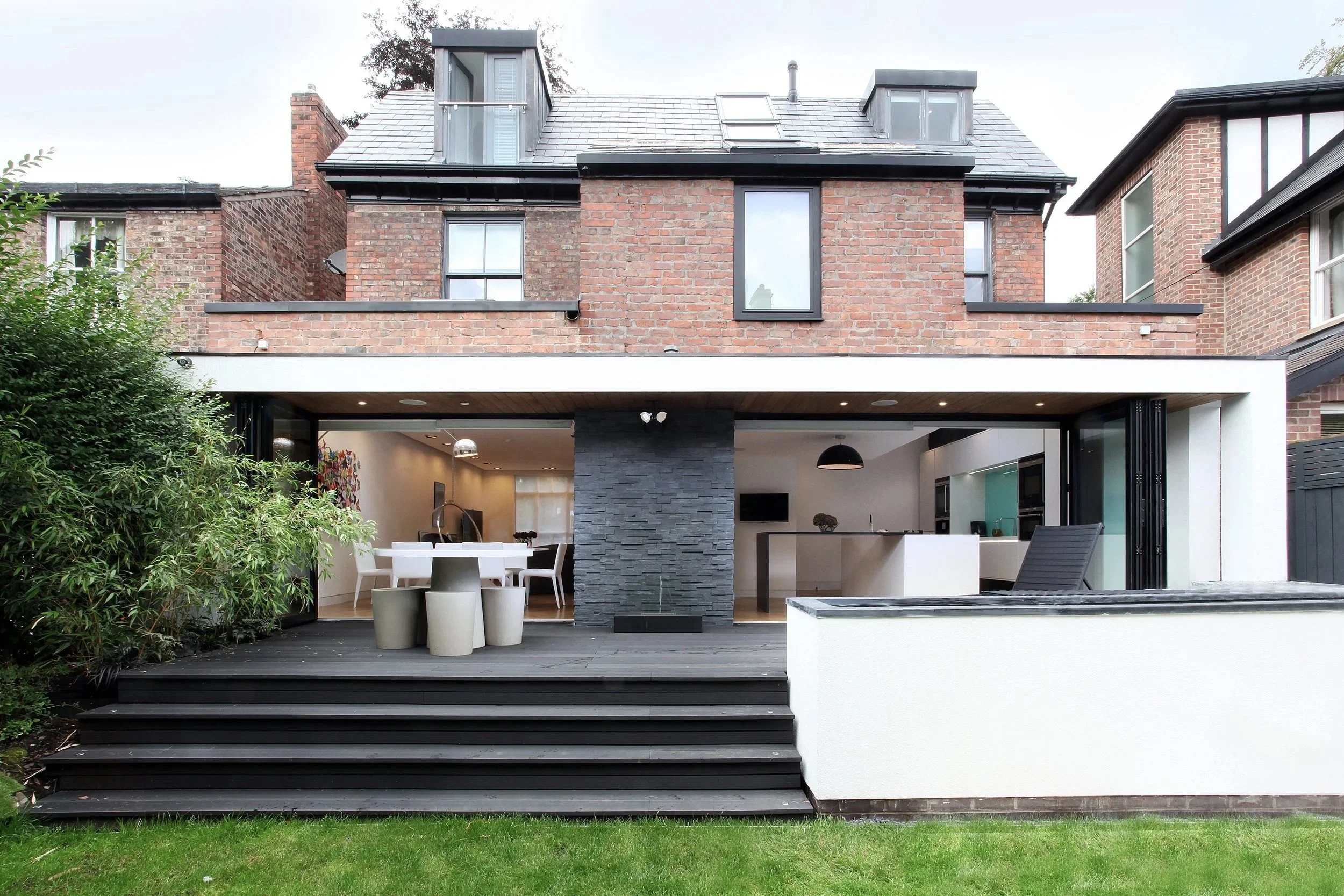 Modern rear extension with decking and raised roofline from loft conversion in Manchester Victorian house renovation and kitchen extension.