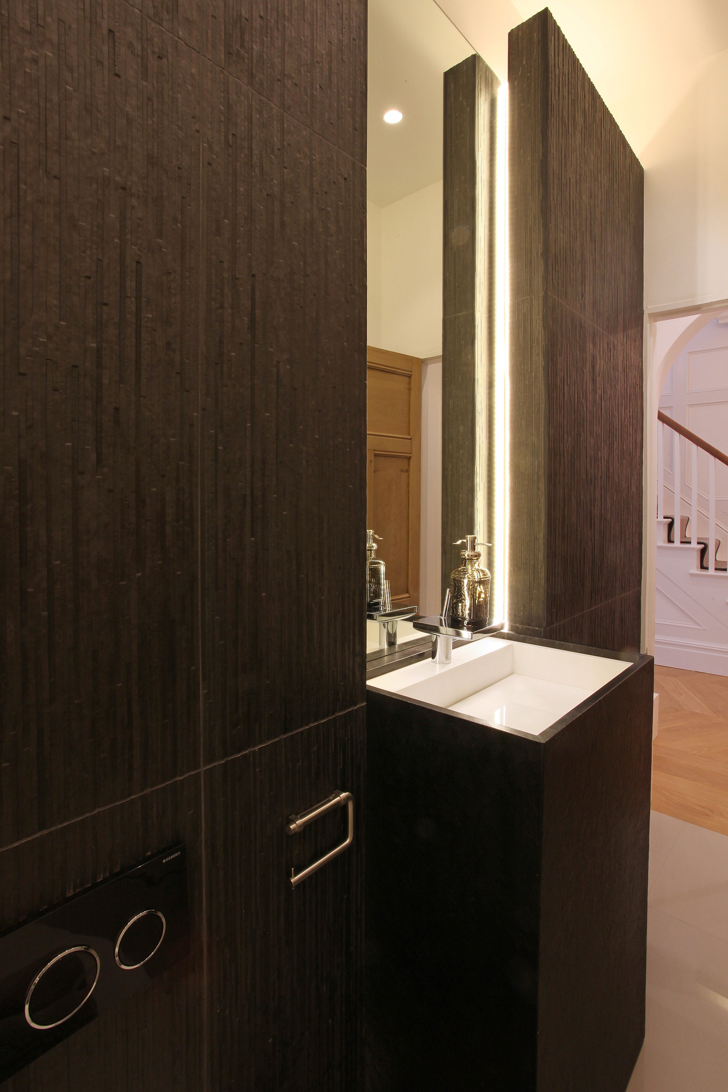 Dark timber panelling and herringbone floor in modern minimal bathroom refurbishment located in West Didsbury, Manchester.