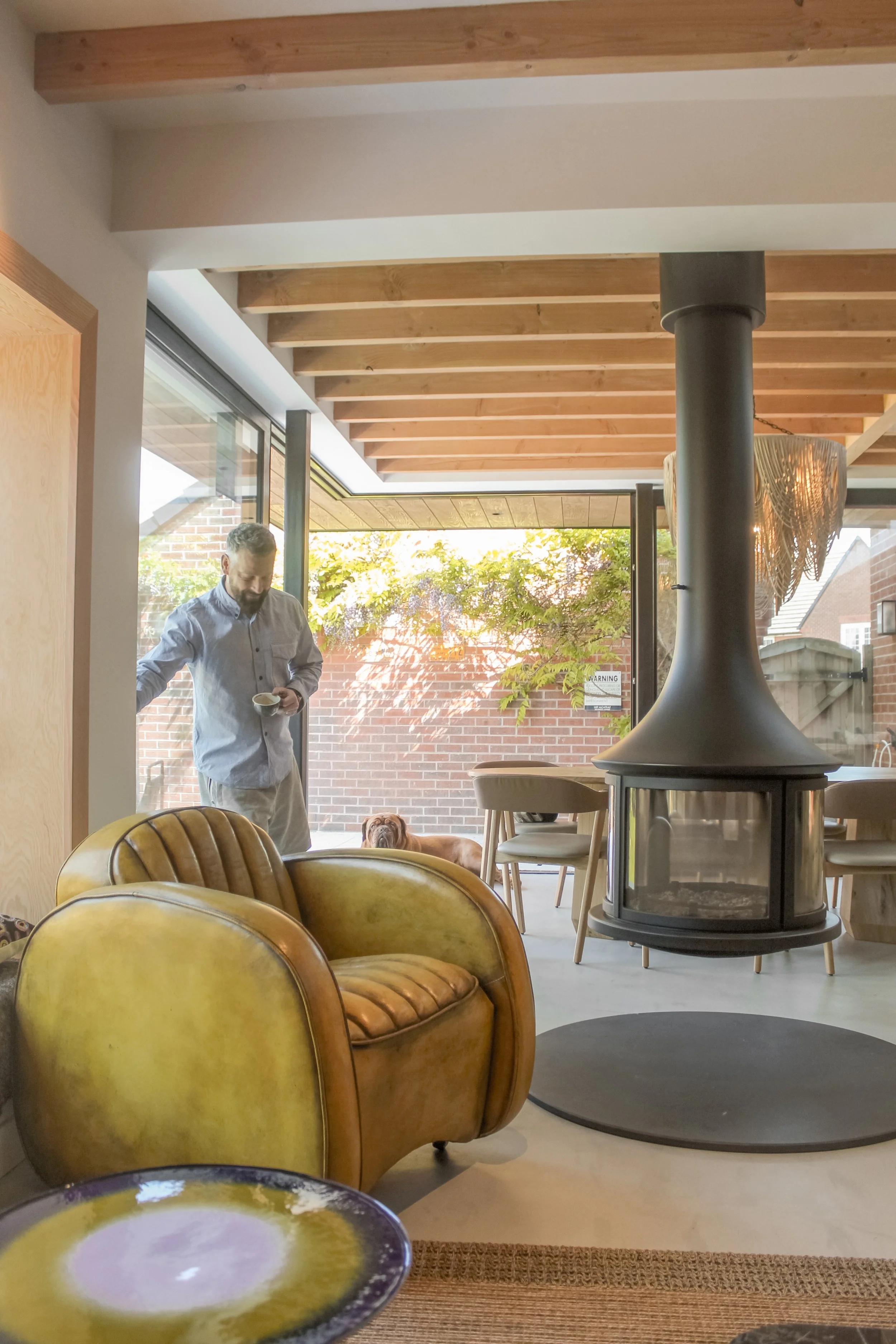 A modern open plan kitchen and living room extension with exposed timber, sliding doors, glass to glass corner and contemporary fireplace. Rear canopy extension with oriel window and interior design in Runcorn.