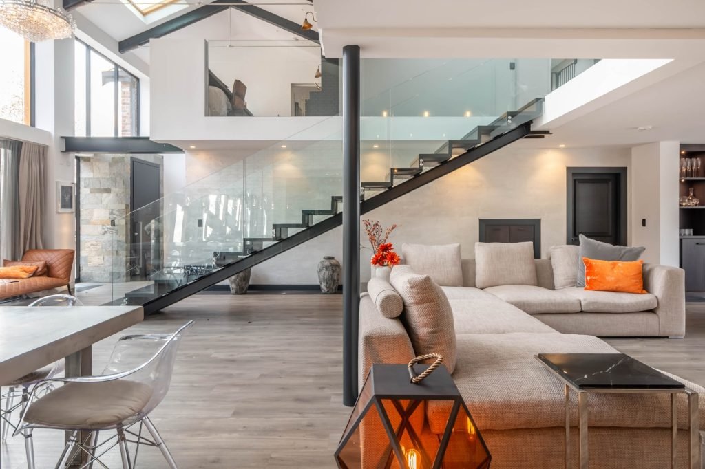 Modern living room with open staircase, large sectional sofa, and decorative accents in a bright, spacious interior.