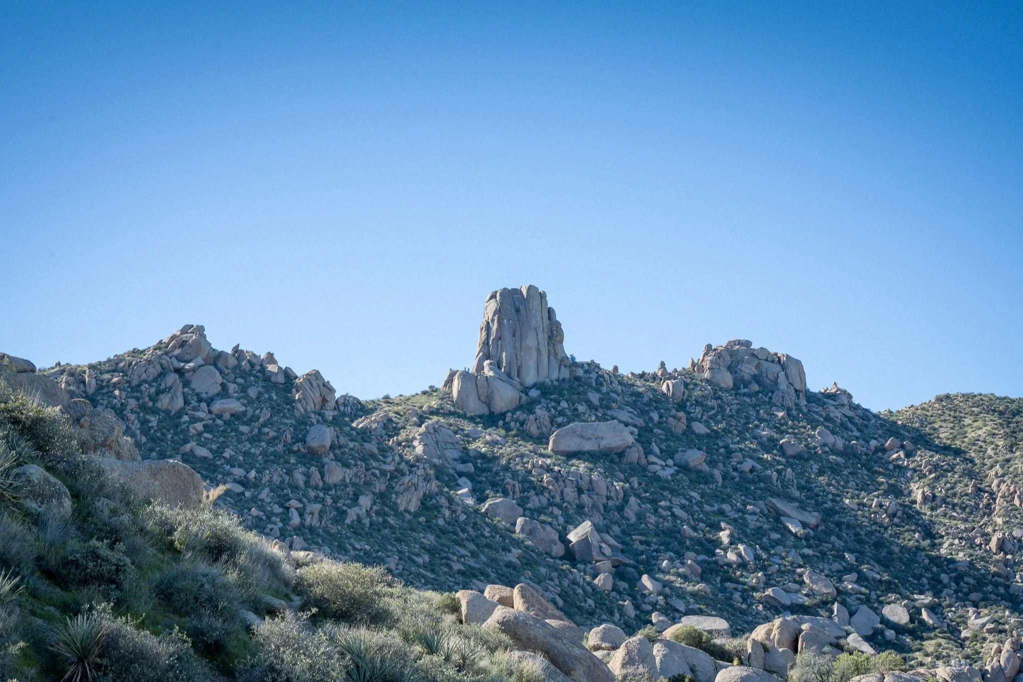 A clear blue sky with a distant view of Tom's Thumb rising on the horizon.