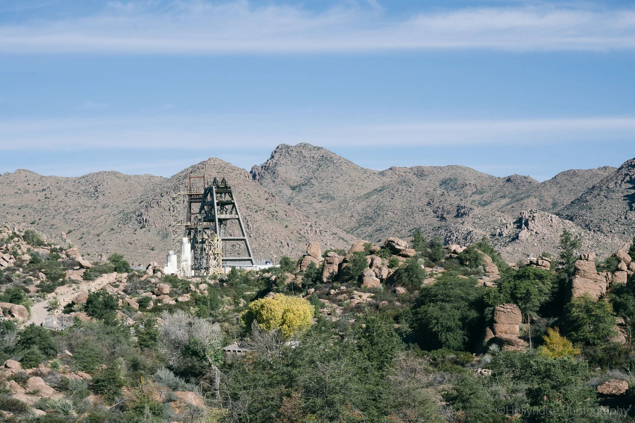 Mine structure visible over desert trees at The Magma Gardens near Superior Arizona with rugged mountains in the background