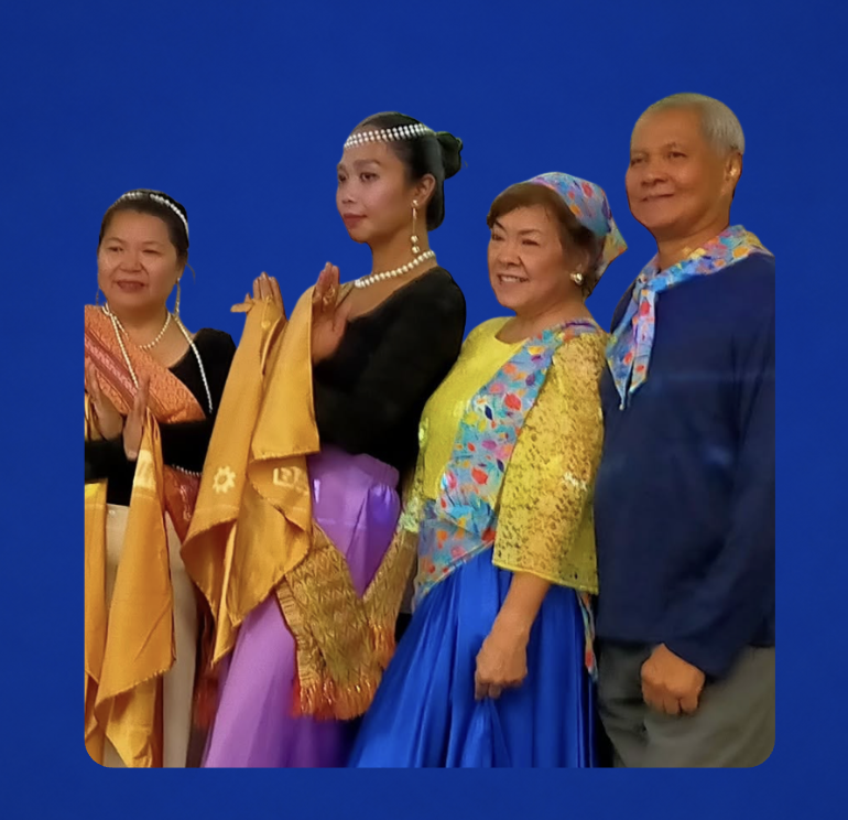 Group of five people dressed in traditional Southeast Asian clothing against a plain blue background.