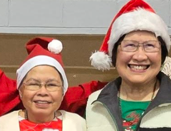 Three people wearing Santa hats smiling and standing together in a holiday setting.