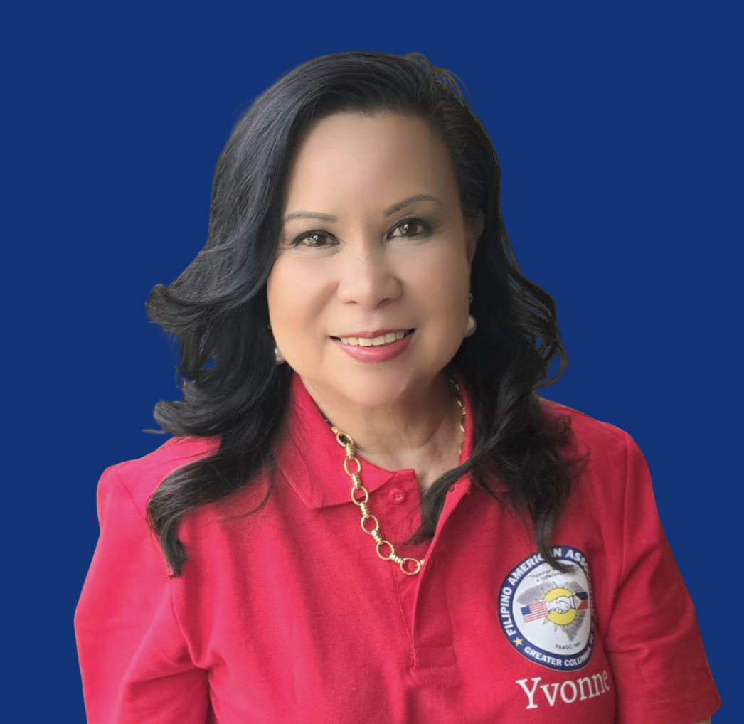 Portrait of a woman with black hair wearing a red shirt with a badge that reads 'Yvonne' and a gold chain necklace, against a dark blue background.