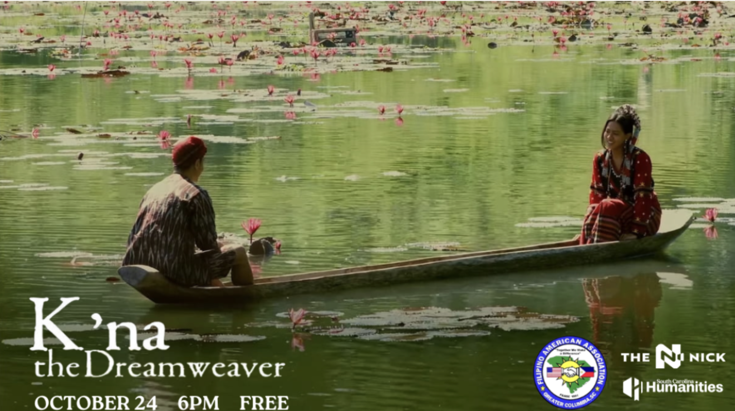 Two women in a boat on a pond filled with blooming pink water lilies. One woman is facing away and the other is smiling at her. The water reflects the green surroundings.