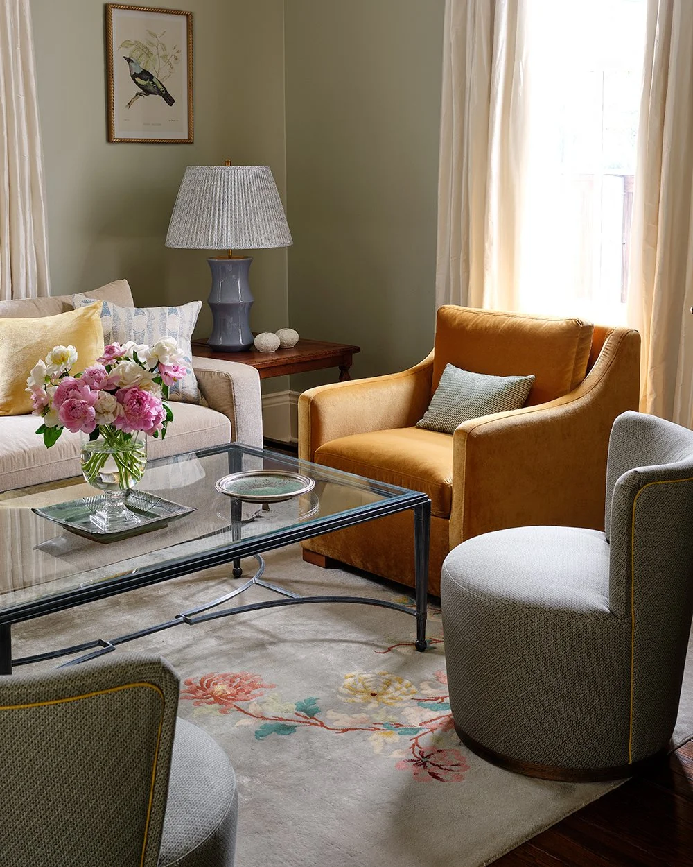 Traditional living room with assorted cushioned seating, glass rectangle coffee table, and a floral rug. 