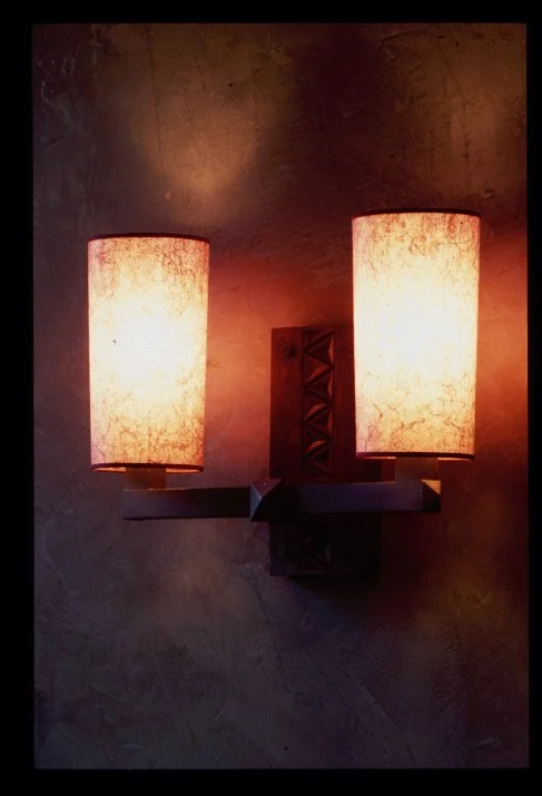 A wall-mounted two-light sconce with fabric shades on a textured wall.


