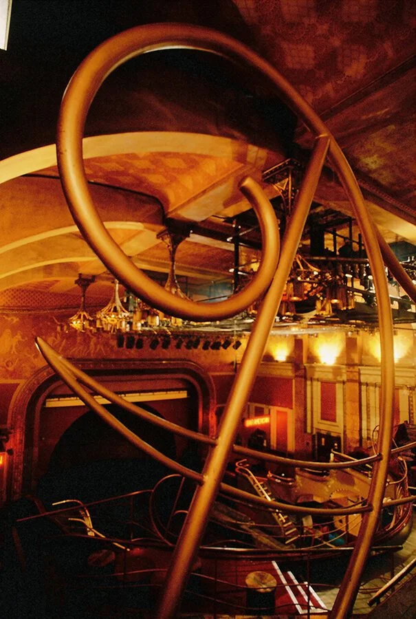 Interior of a theater with a large, abstract metallic sculpture and tiered seating.




