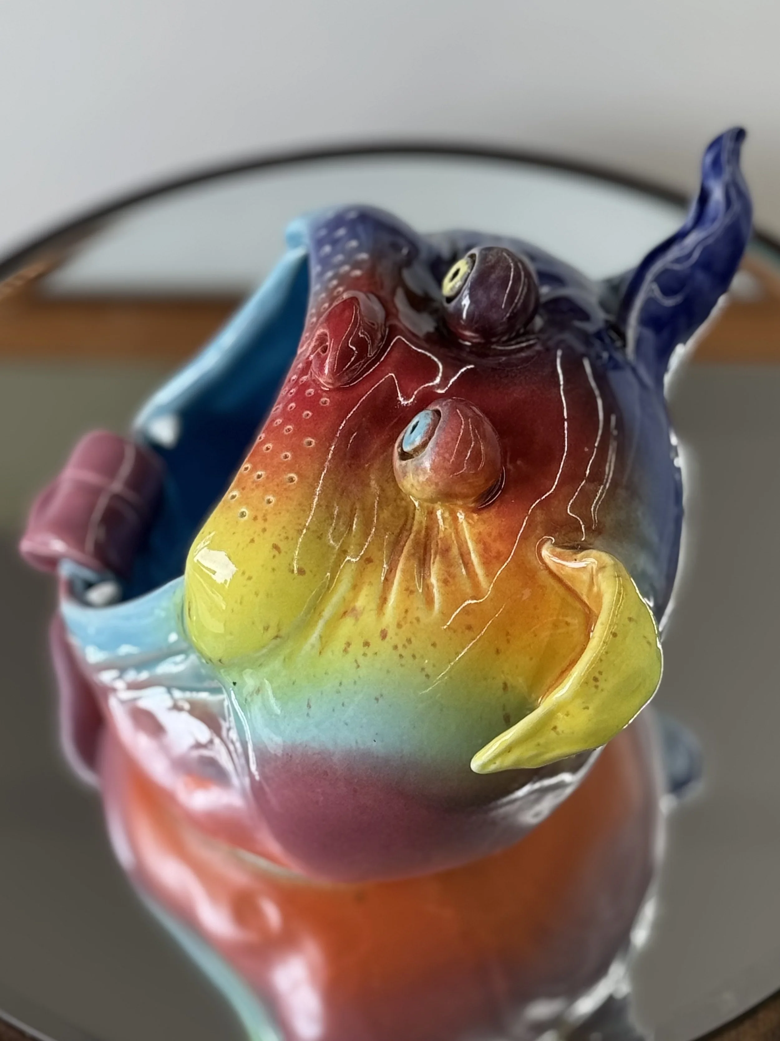 Colorful ceramic dog head with a rainbow gradient finish, seen from above.