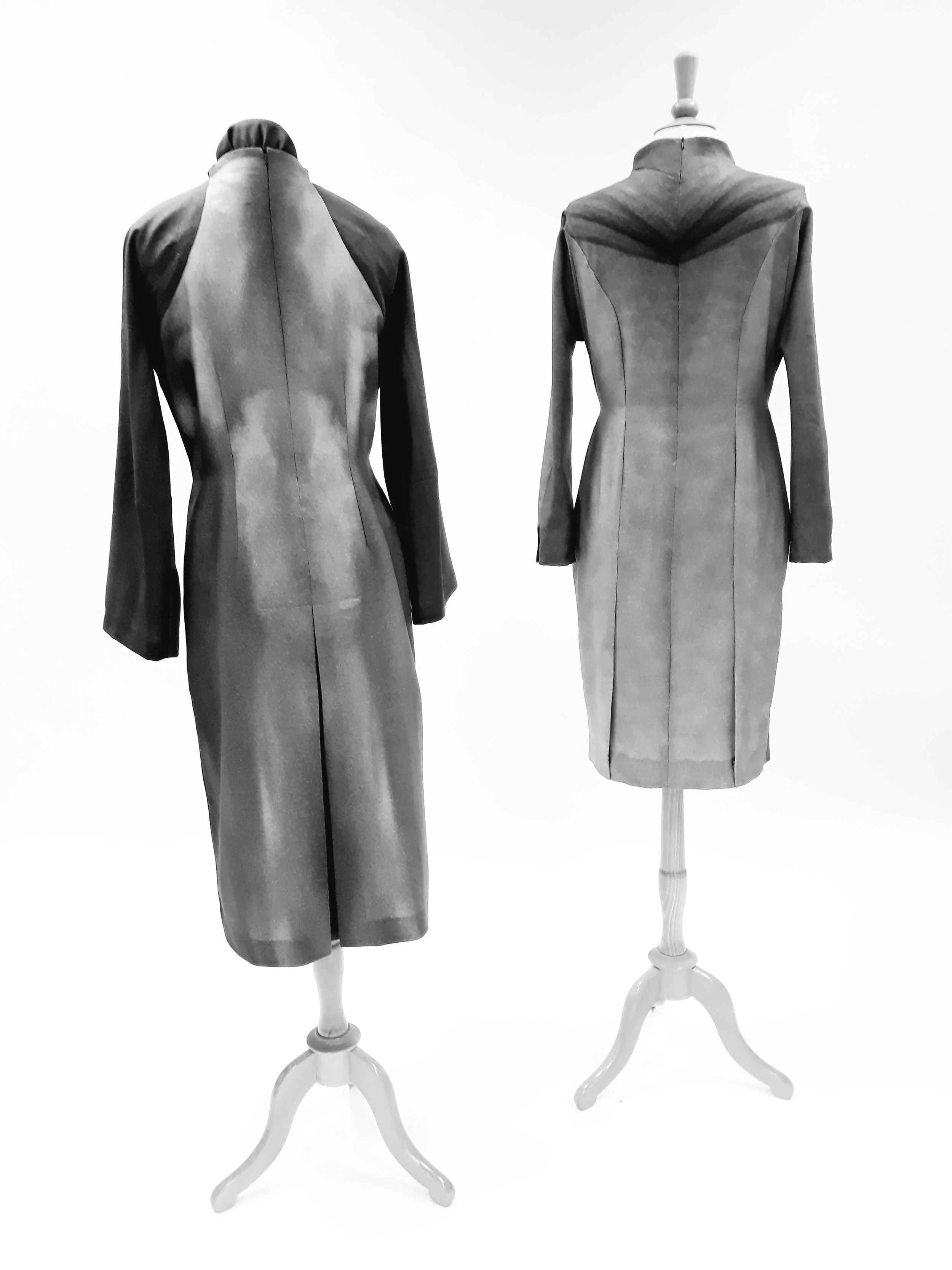 Two mannequin dress forms displaying vintage-style dresses, one on the left with a dress that has a high collar, and one on the right with a fitted dress that has a wide collar, both on white stands against a plain white background.