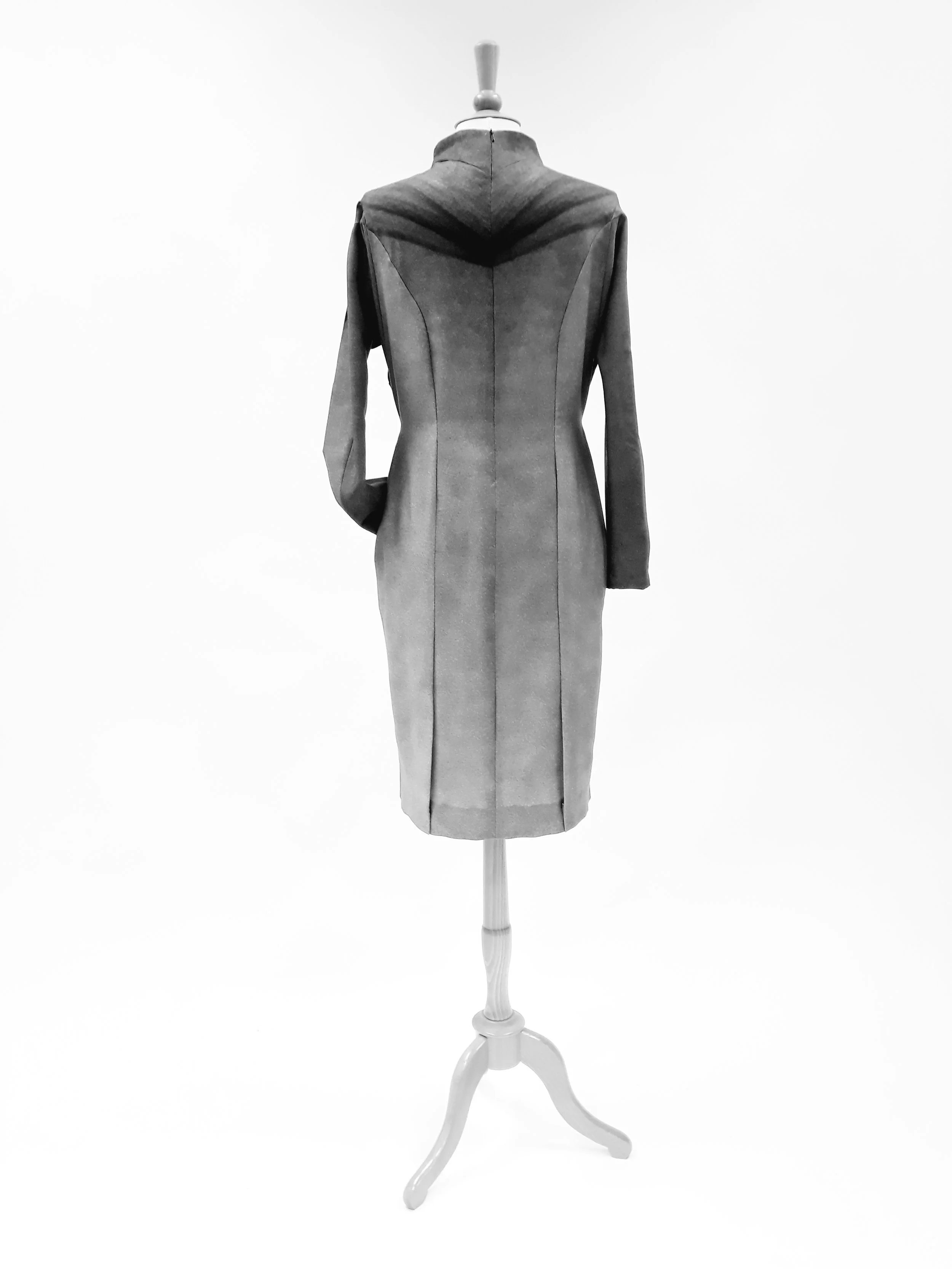 A mannequin dressed in a vintage style coat on a white display stand.