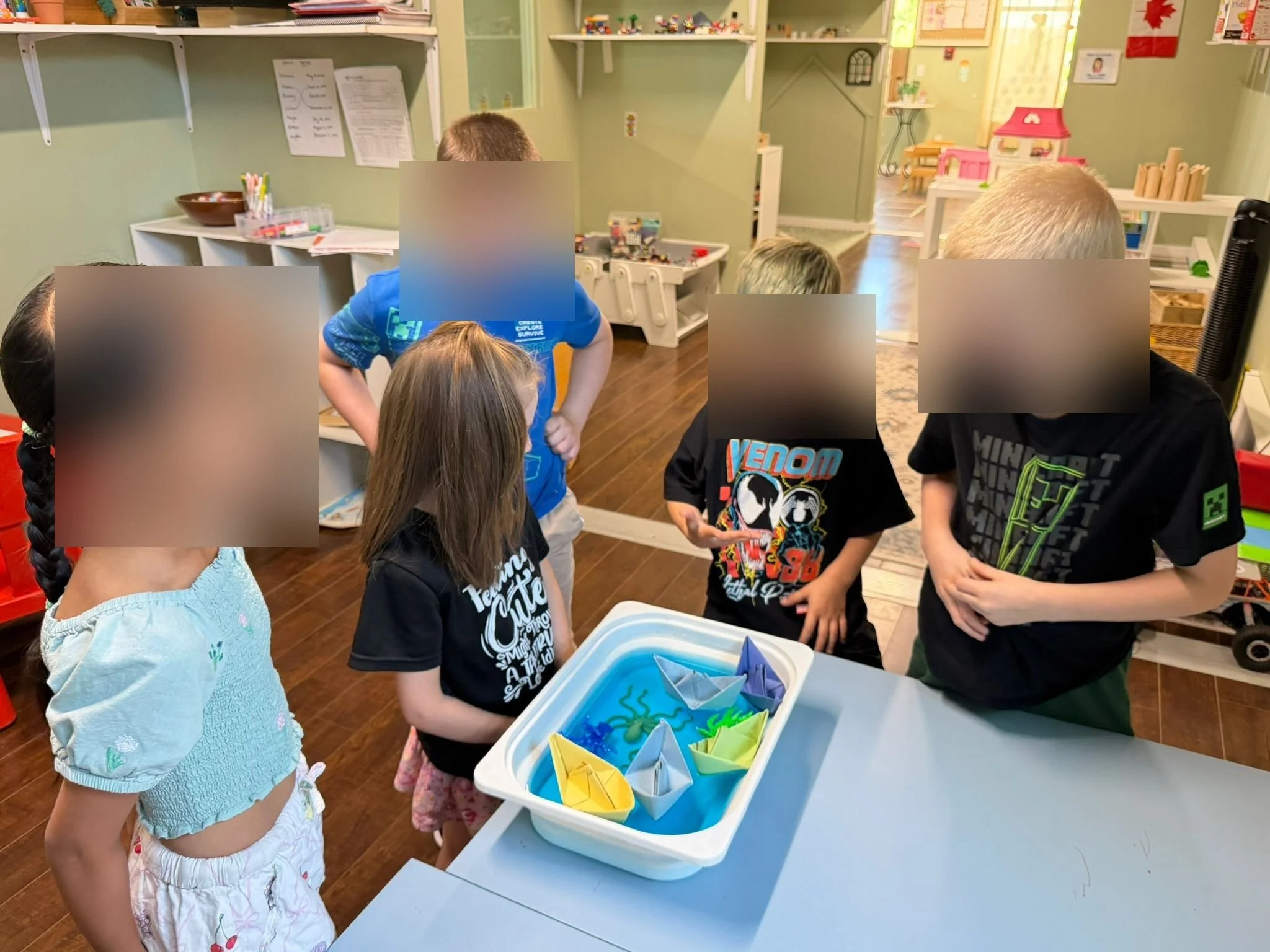 Children around a sensory bin with origami boats